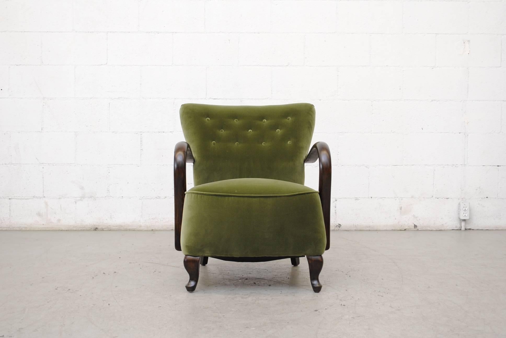 Gorgeous plump olive velvet tufted lounge chair with dark wood ribbon-like arm rests and fat claw-like feet. Frame in good original condition.