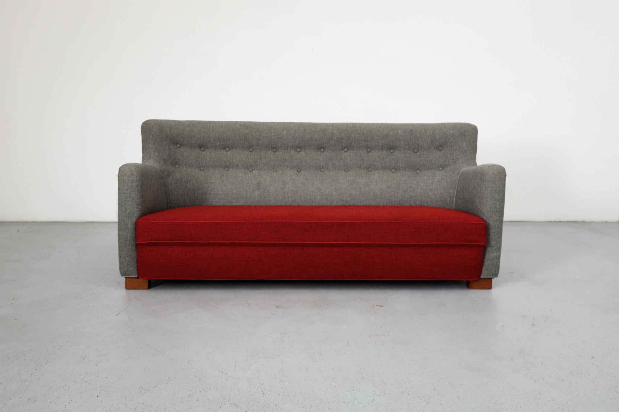Sofá de tres plazas de estilo vintage Theo Ruth, con estructura tapizada en lana gris y asiento de tela de lana roja. Sofá empenachado bien construido con curvas en picado, botones y patas de madera. En estado original con desgaste visible acorde