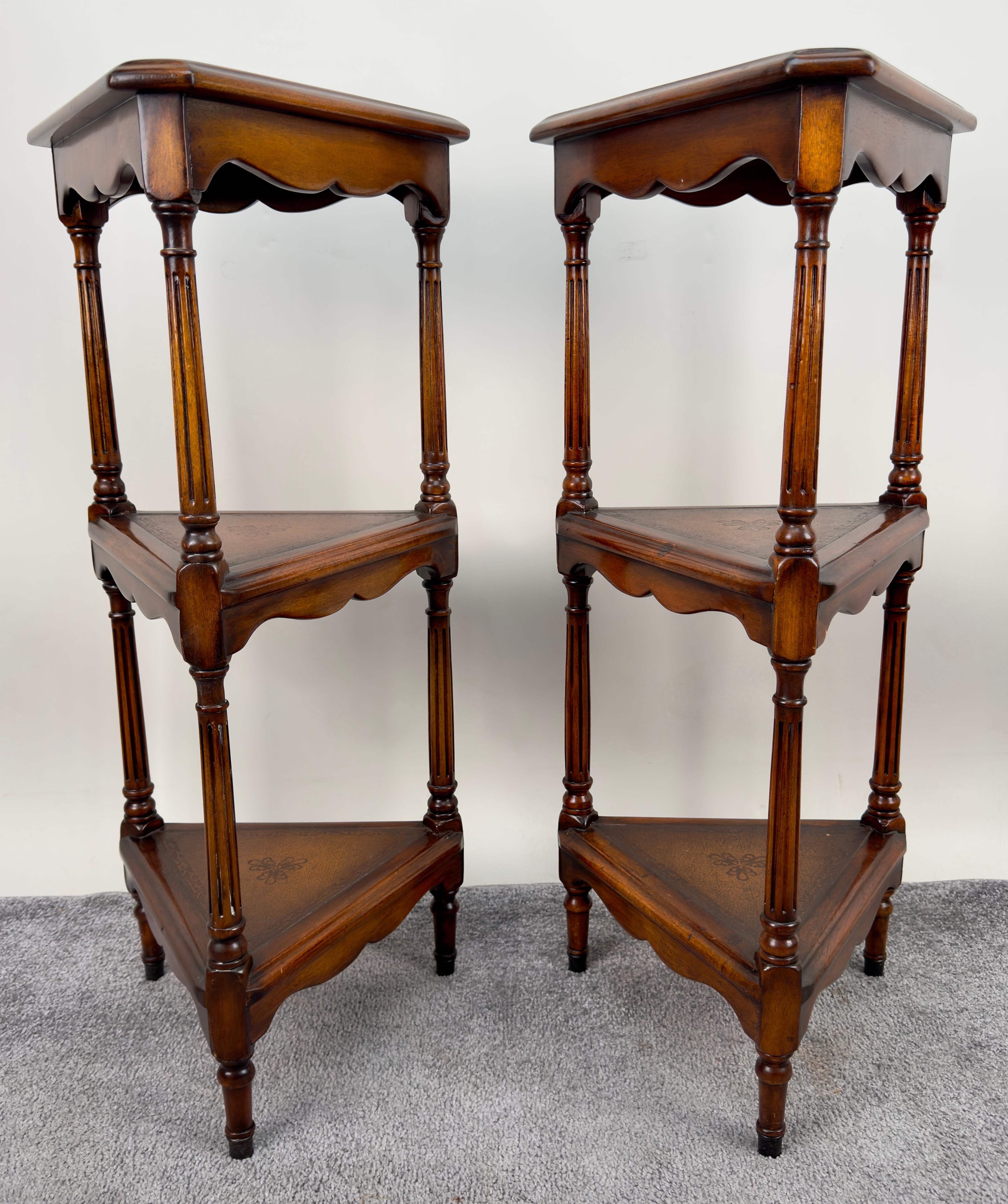 An elegant pair of Hollywood Regency Style Mahogany 3 tiered Pedestals or etageres Designed by Theodor Alexander and made in Vietnam. The beautiful pedestals feature three triangle leather tooled shelves to display plants or decor pieces and