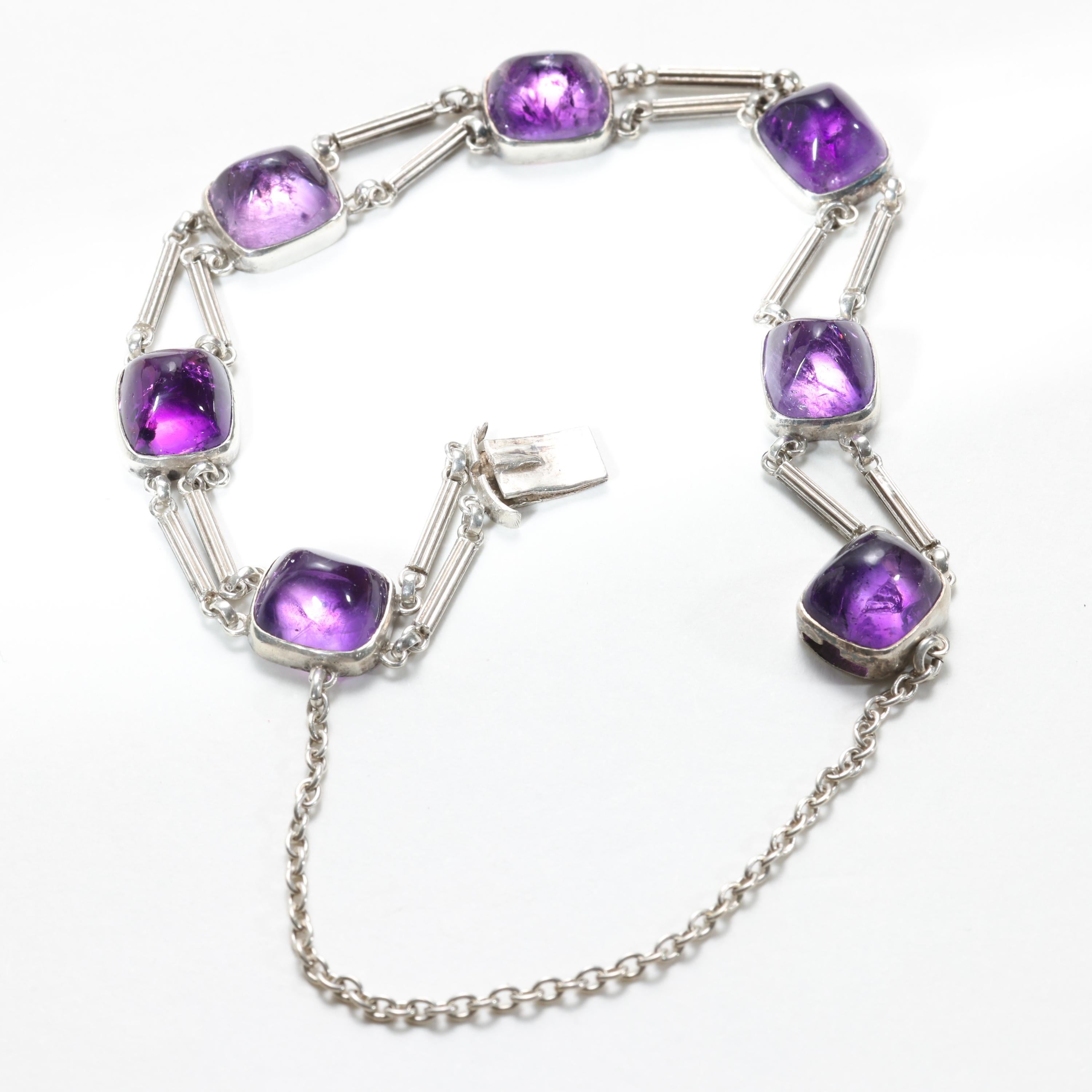 This rare and exquisite bracelet by renowned jewelry manufacturer, Theodor Fahrner is crafted in silver and set with sugarloaf cabochons of natural amethyst. 

Created in the early 1900s, this dainty yet powerful bracelet reflects the Jugendstil