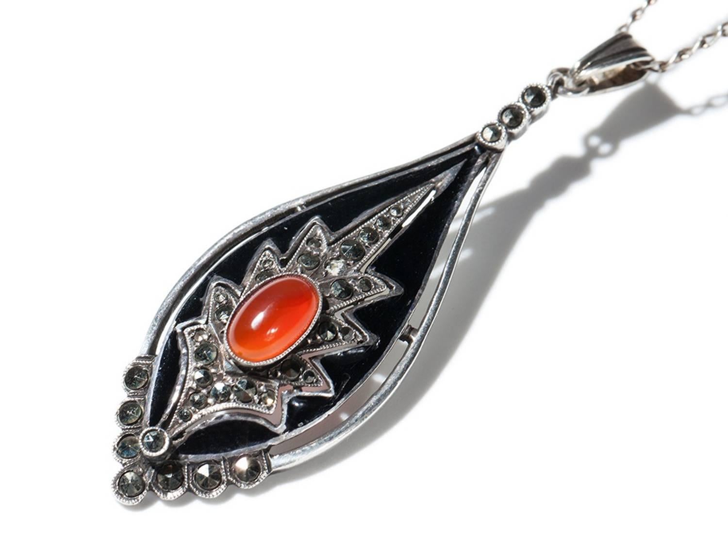 Teardrop-shaped black enamel pendant. Decorated with carnelian cabochon and marcasites. Silver. Marked on the back side: GERMANY STERLING TF. Total weight: 4.9 grams. A beautiful example of Theodor Fahrner’s jewellery art. 
Length: pendant 2.09 in (