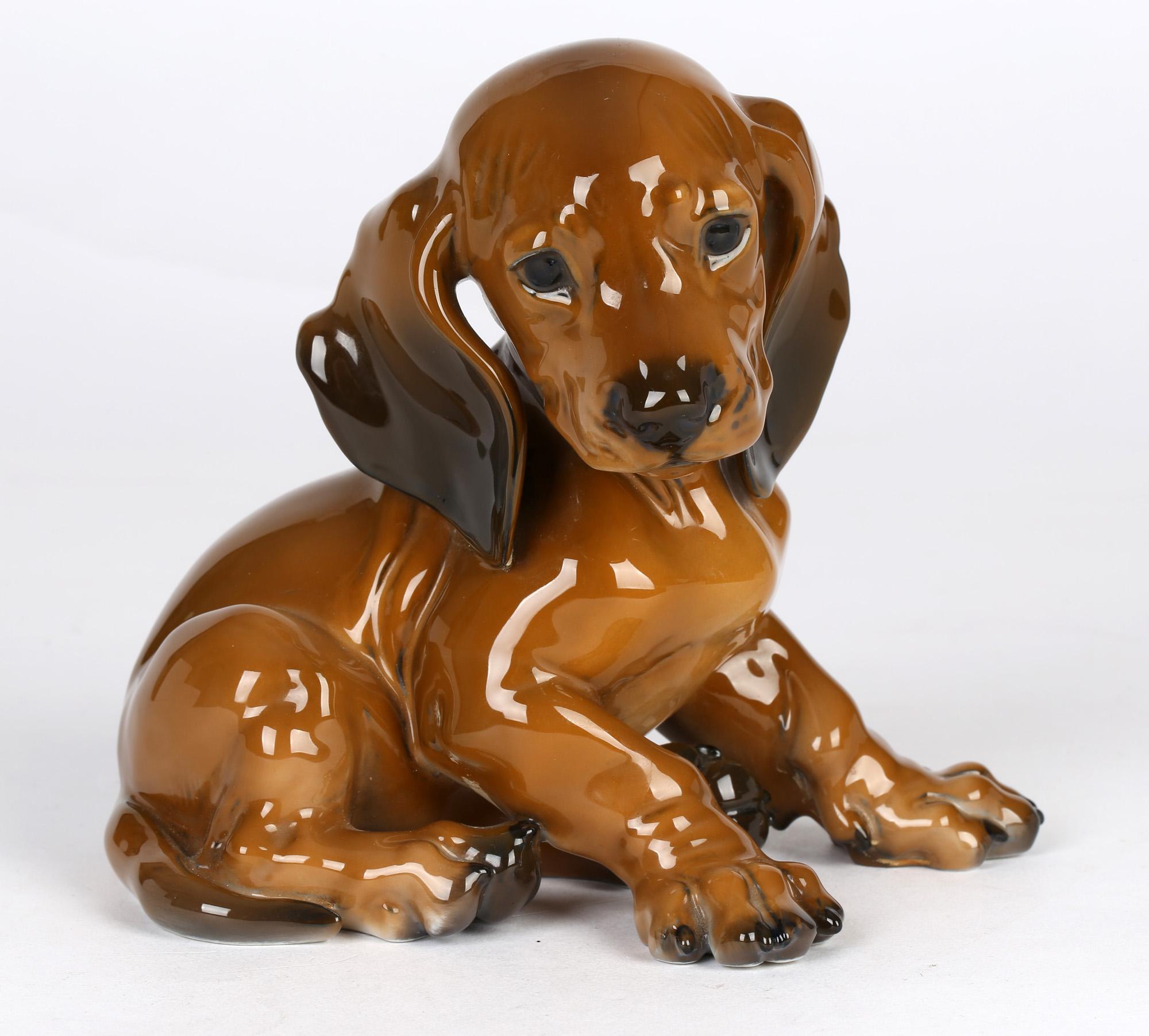 A finely made German mid-century porcelain figure of a dachshund puppy by Theodor Karner dating from the 1950/60's. The hand made figure is modeled seated on its hind legs with its head held to one side. It is beautifully modeled with wonderful