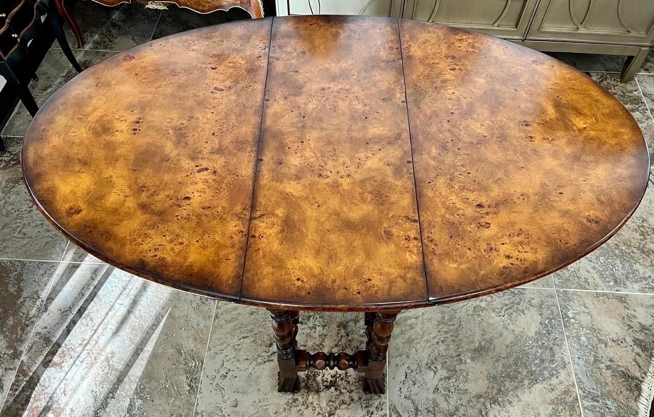 A handsome Theodore Alexander antiqued gate-leg dining table, the oval drop-leaf top above to end frieze drawers, on turned legs joined by stretchers.  The original 17th century English.

Table measures 58