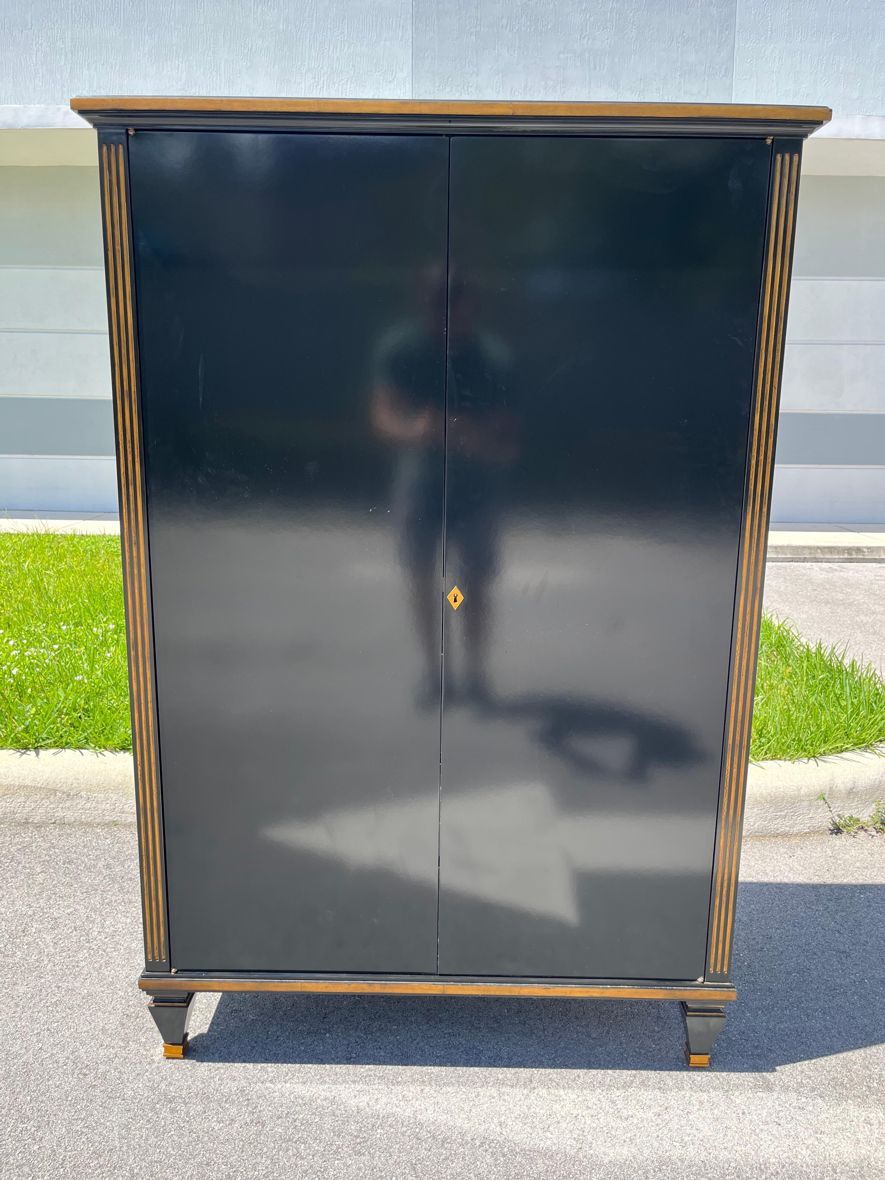 Mobile Theodore Alexander, laccato nero con dettagli dorati. L'interno è dotato di tre cassetti e un ripiano in vetro. Viene fornito con una chiave.