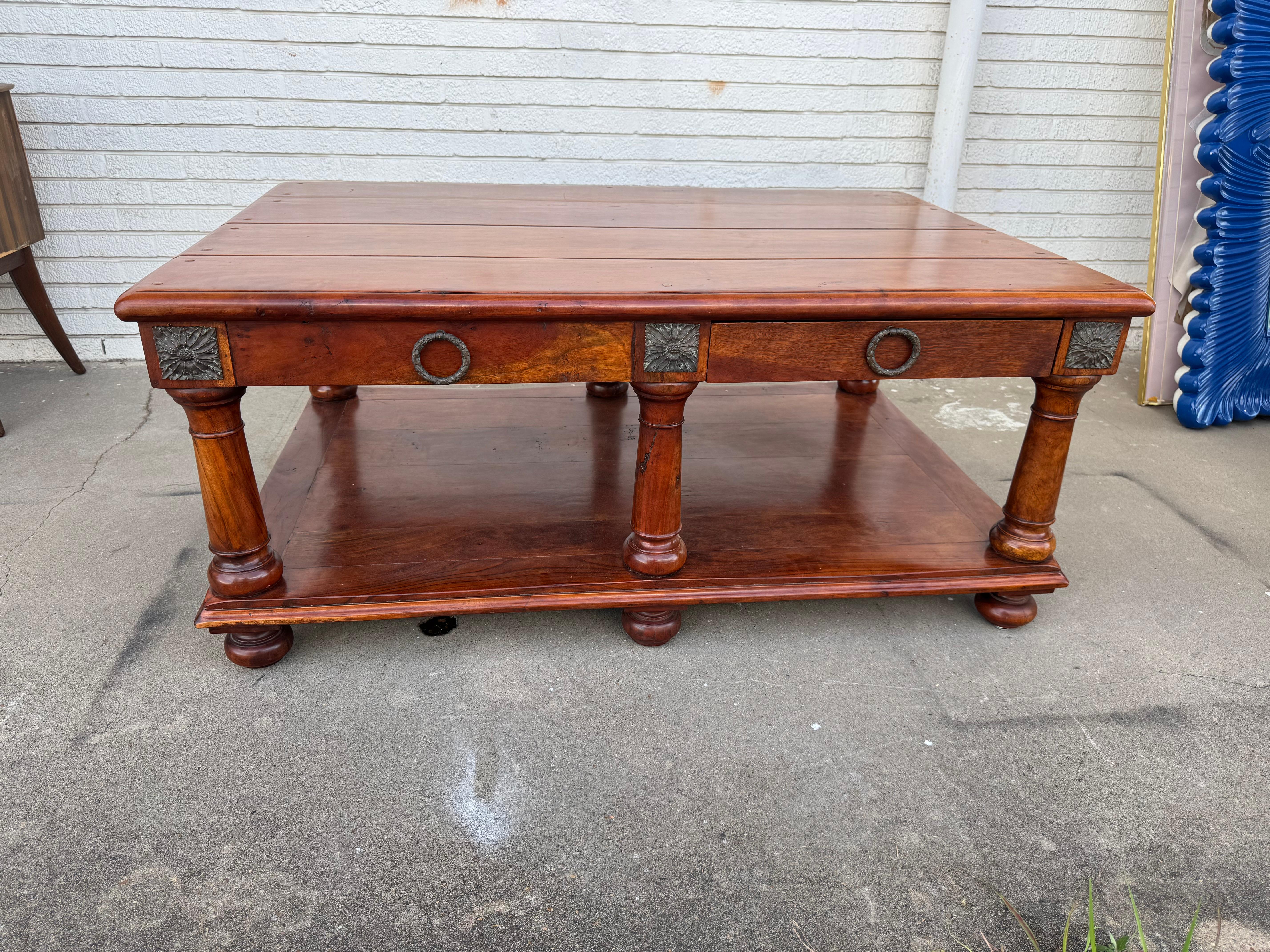 This is a very heavy, solid wood coffee table by Theodore Alexander.
The table is made of cherrywood.
It has 6 legs for added support.
The legs have antiqued ormolu on the skirt.
There's an added shelf on the bottom for extra storage.
