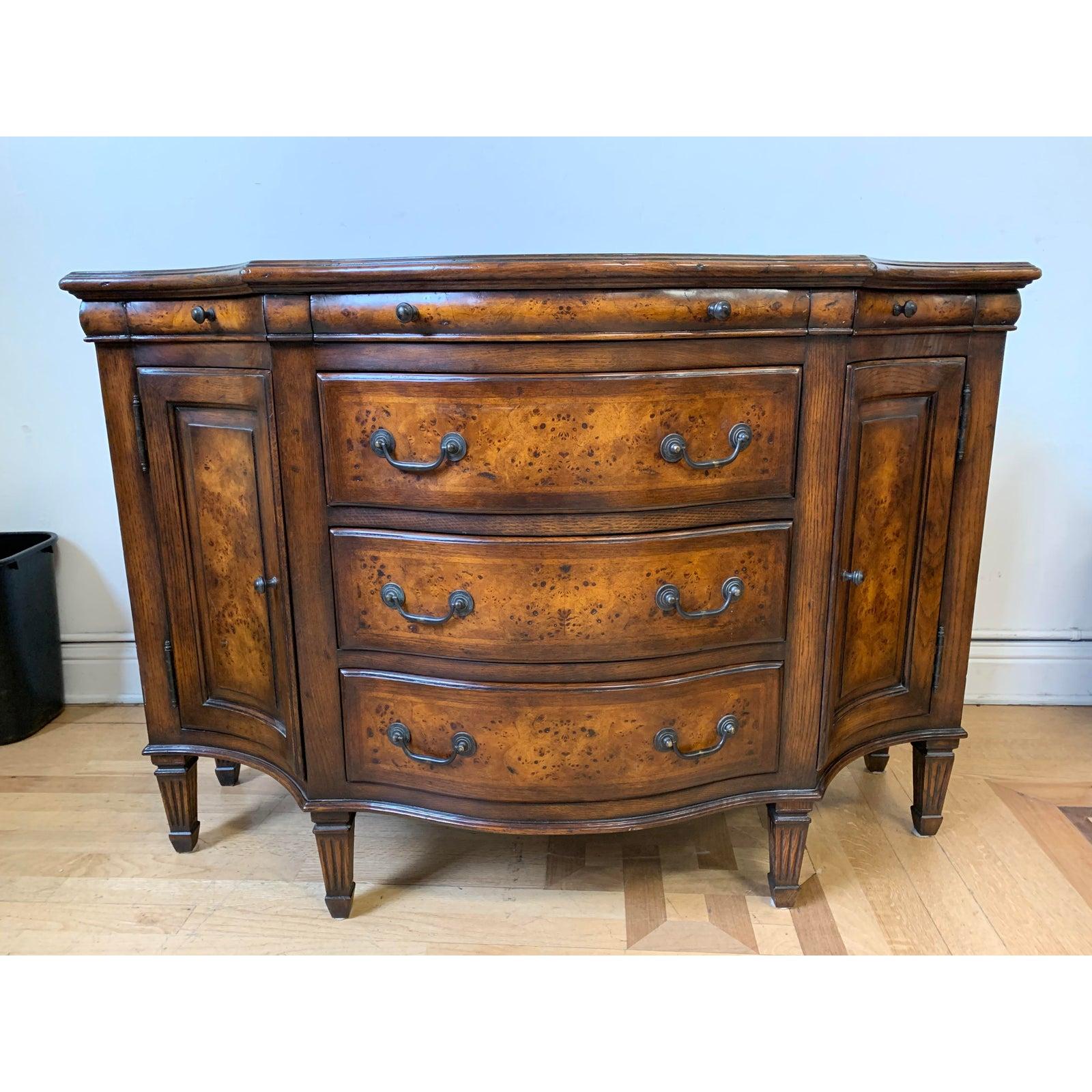 A Theodore Alexander curved front sideboard. Beautiful burled maple wood is contrasted with traditional lines and French inspired curved. Three shallow drawers on top make full use of the form with interior space on top. Three drawers of equal size