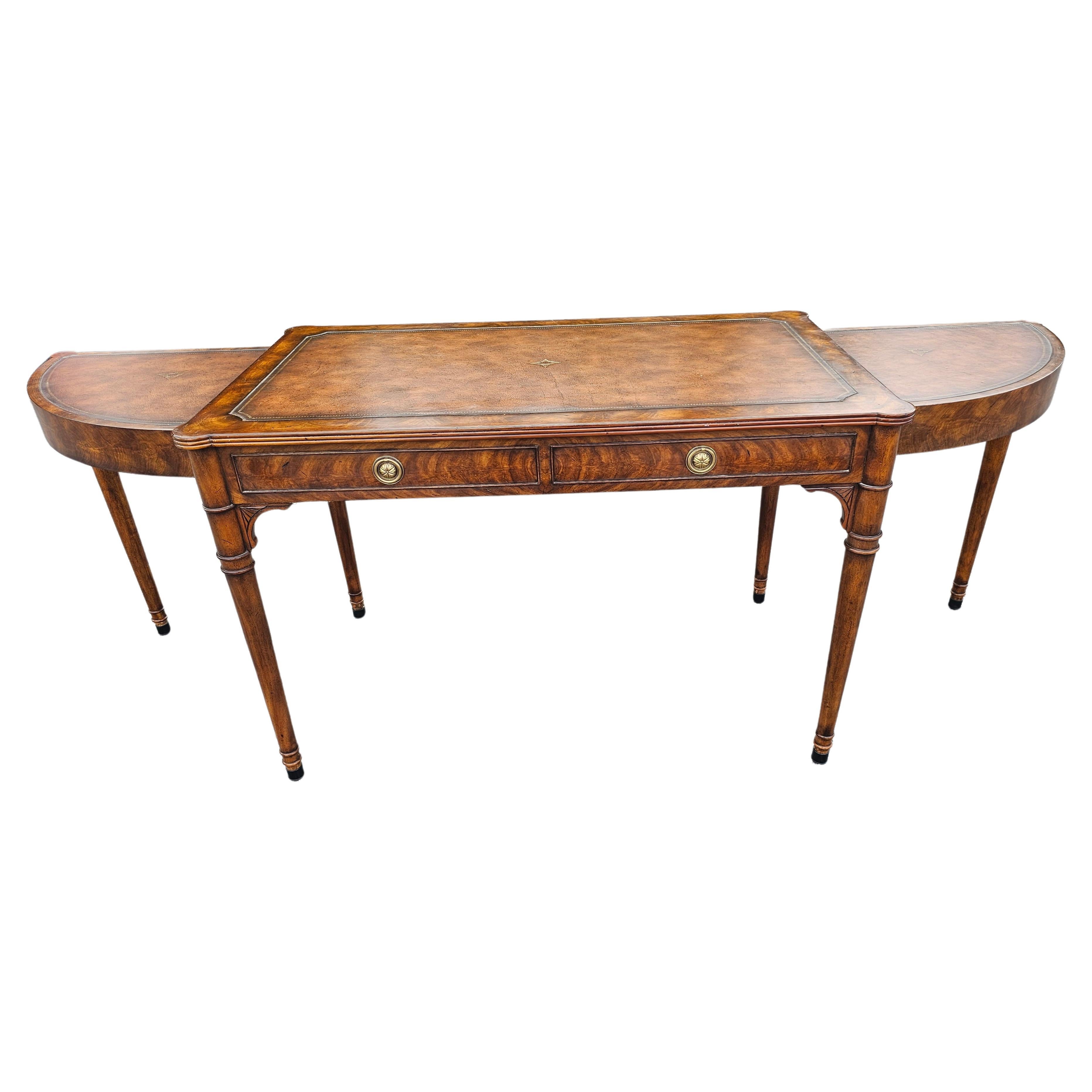 An Exquisite Theodore Alexander Extendable Mahogany and Tooled Leather Top Writing Desk. Banded and Tooled top. Two drawers and faux drawers on front and back. Measures 79