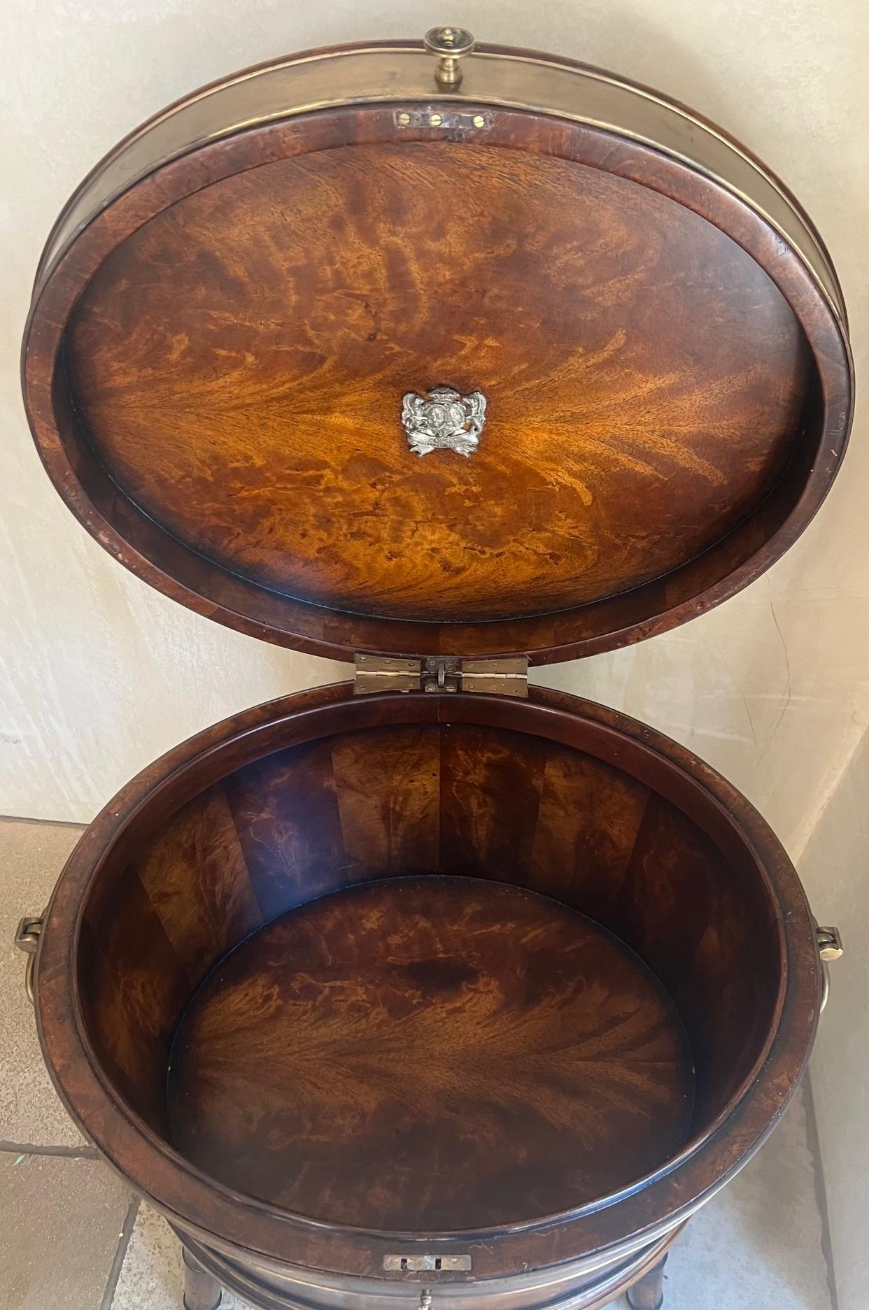Hand made oval cellarette made of mahogany and banded in brass by the Theodore Alexander furniture company in the 1990's for their Althorp Collection. The piece has a hinged lid and fluted legs on castors, with brass handles and a pull, plus two