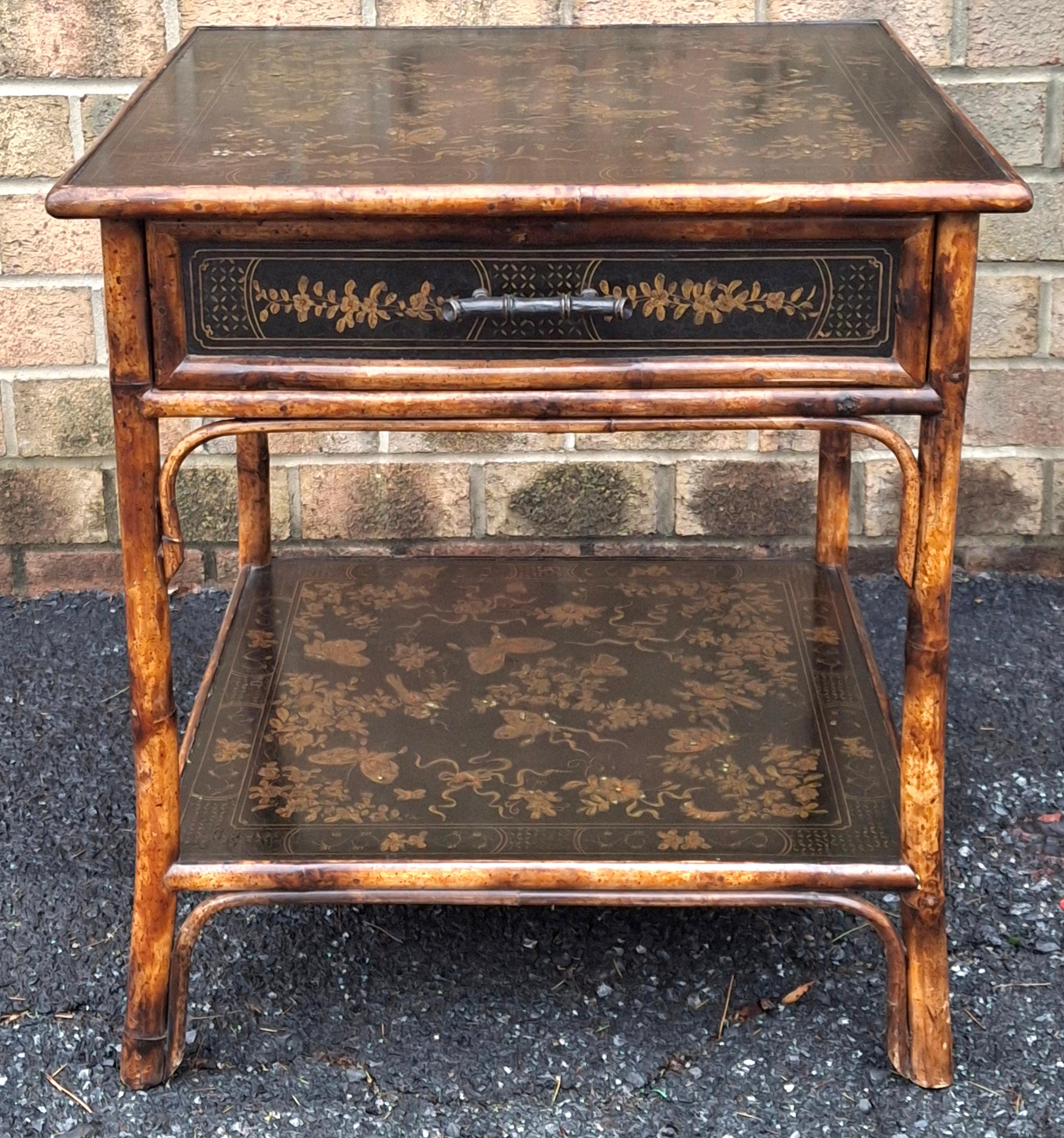 A refined and richly detailed, black Japanned side table by Theodore Alexander. The rattan bamboo frames are finished in a warm burnished tone, evoking 19th-century anglo-Japanese style while the tops and drawer is adorned in intricate hand-painted