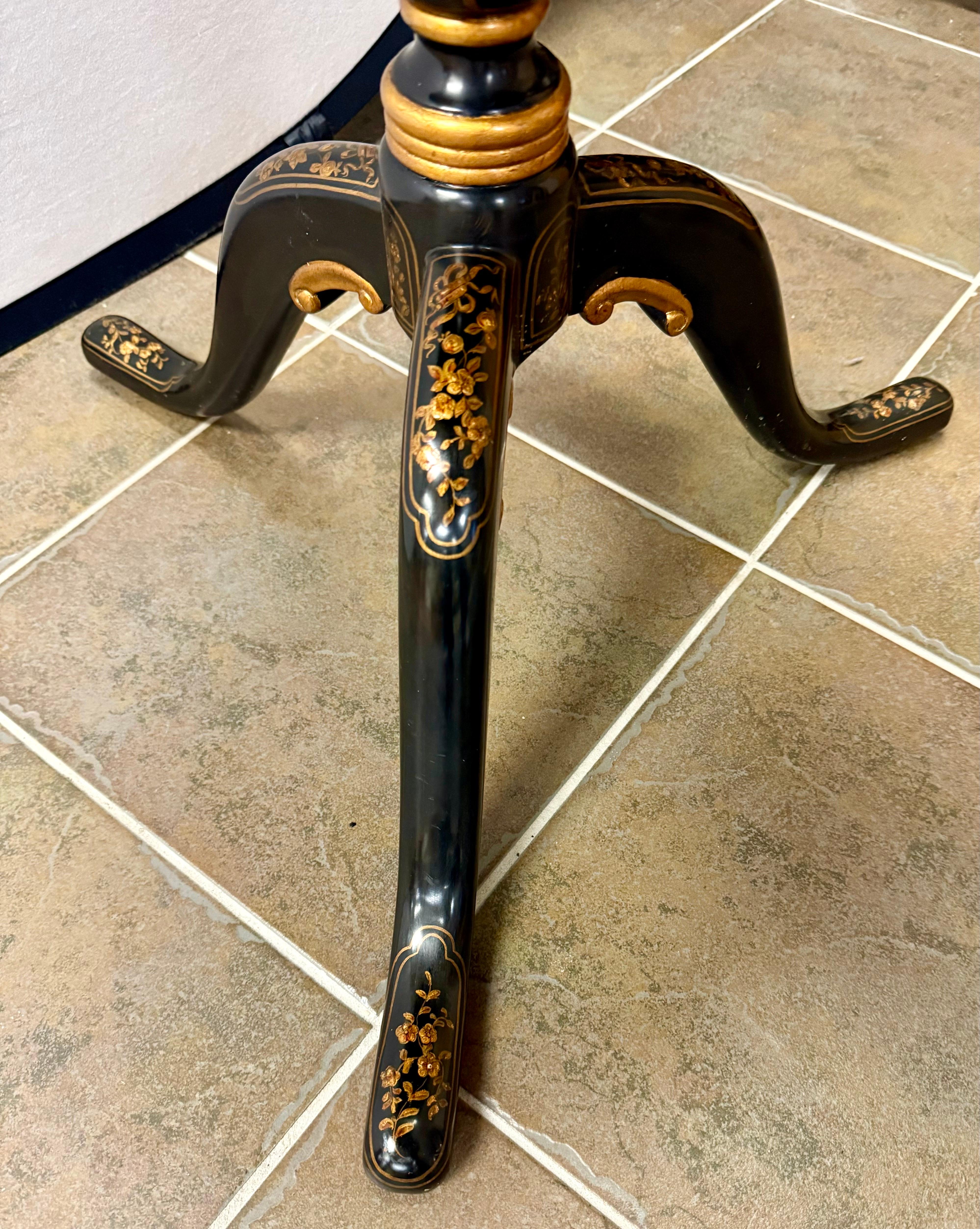 An exquisite black lacquered side table by Theodore Alexander.  The top is supported by a tripod base with down-swept legs leading to queen anne feet.  The table is decorated with gold paint butterflies.  Great for use as a tea table or cocktail