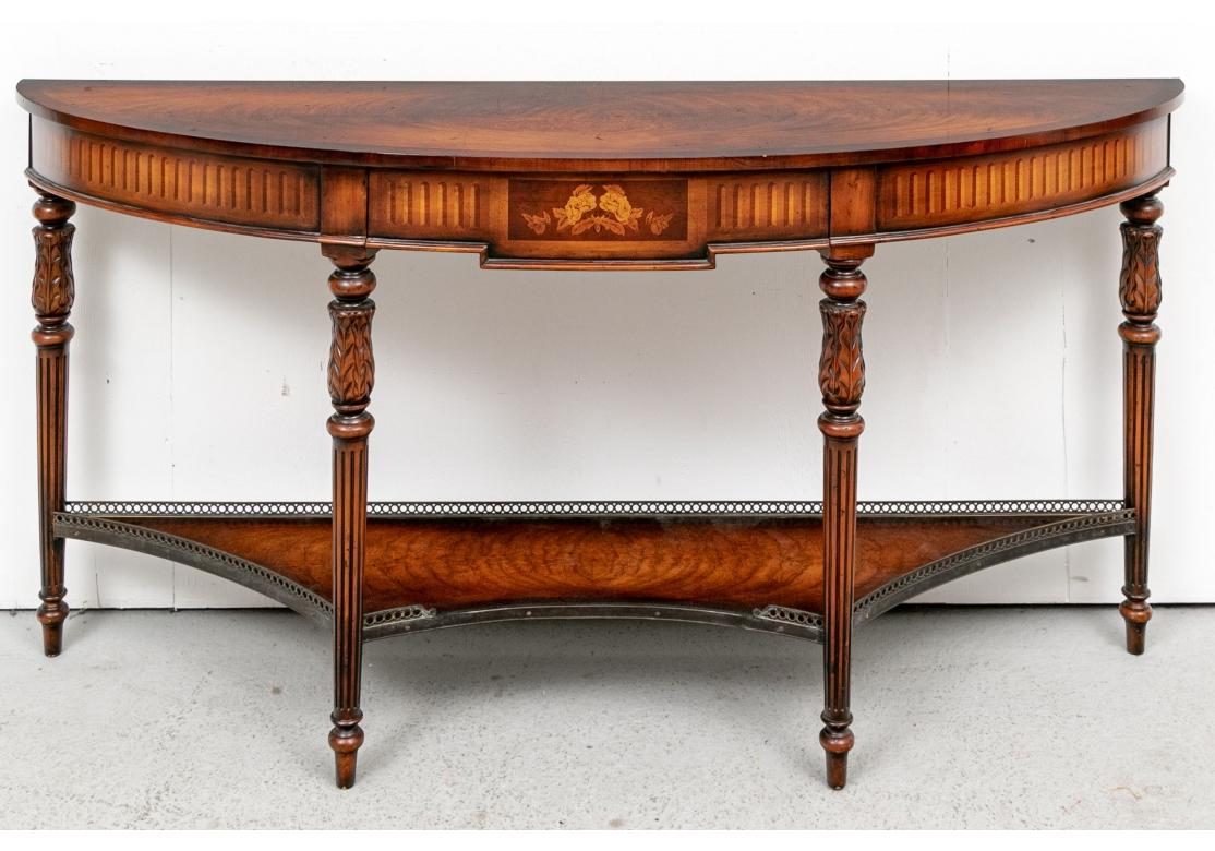 Finely constructed with a book matched banded top. The frieze with a center drawer with marquetry foliate decoration flanked by long two tone parquetry bands. The shaped lower tier also in fine book matched and banded mahogany with brass gallery.