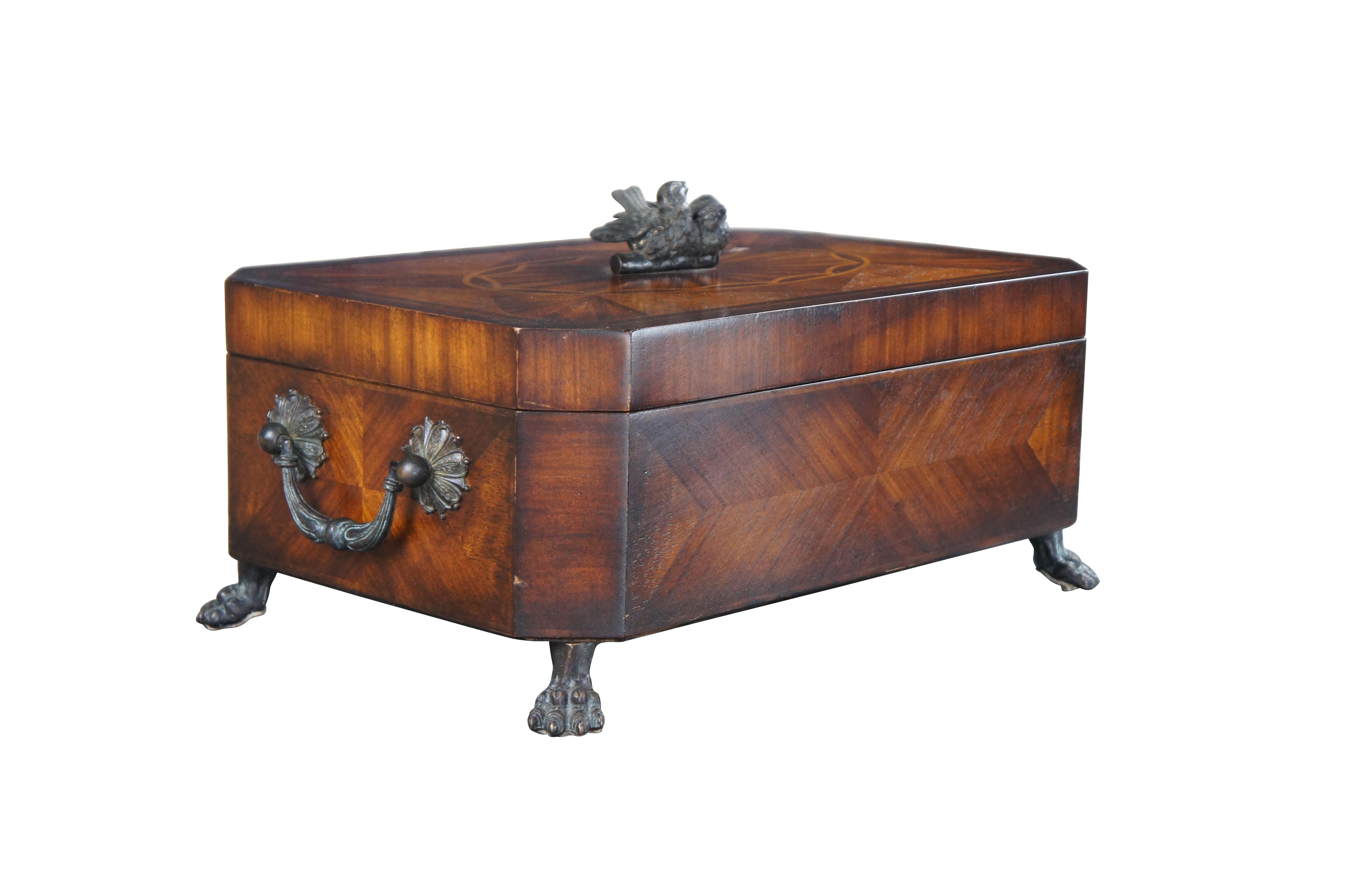 Theodore Alexander keepsake, trinket box or casket.  Features a matchbook veneer mahogany frame with parquetry top and dove finial.  Includes two handles along the sides and claw feet.  The marquetry inlay top is inspired by the meticulous inlays