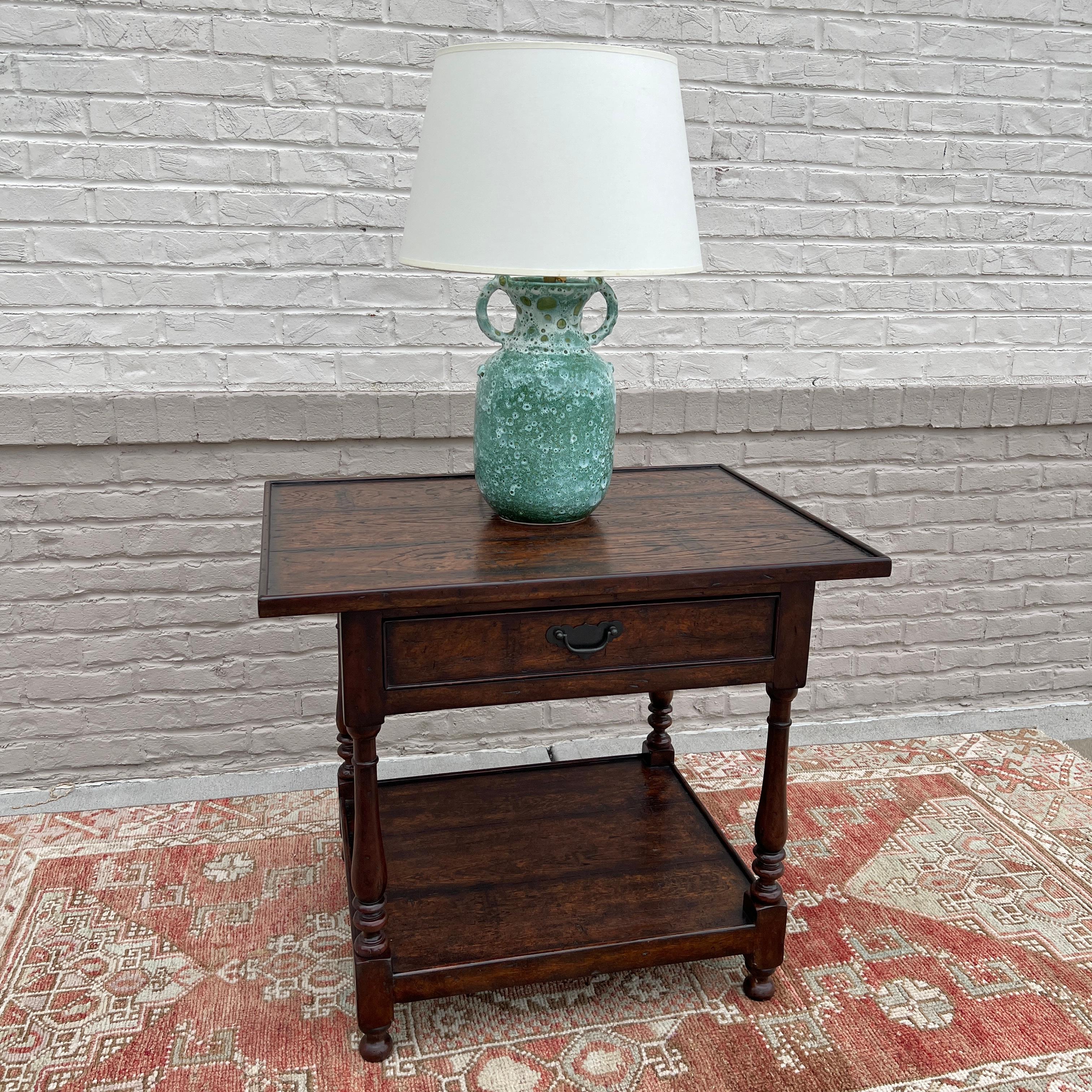 This table is showroom new and has never been used. 

A reclaimed oak veneered and mahogany accent table by Theodore Alexander. Features a planked top, functioning drawer, baluster turned legs and lower shelf. 

Dimensions: 30