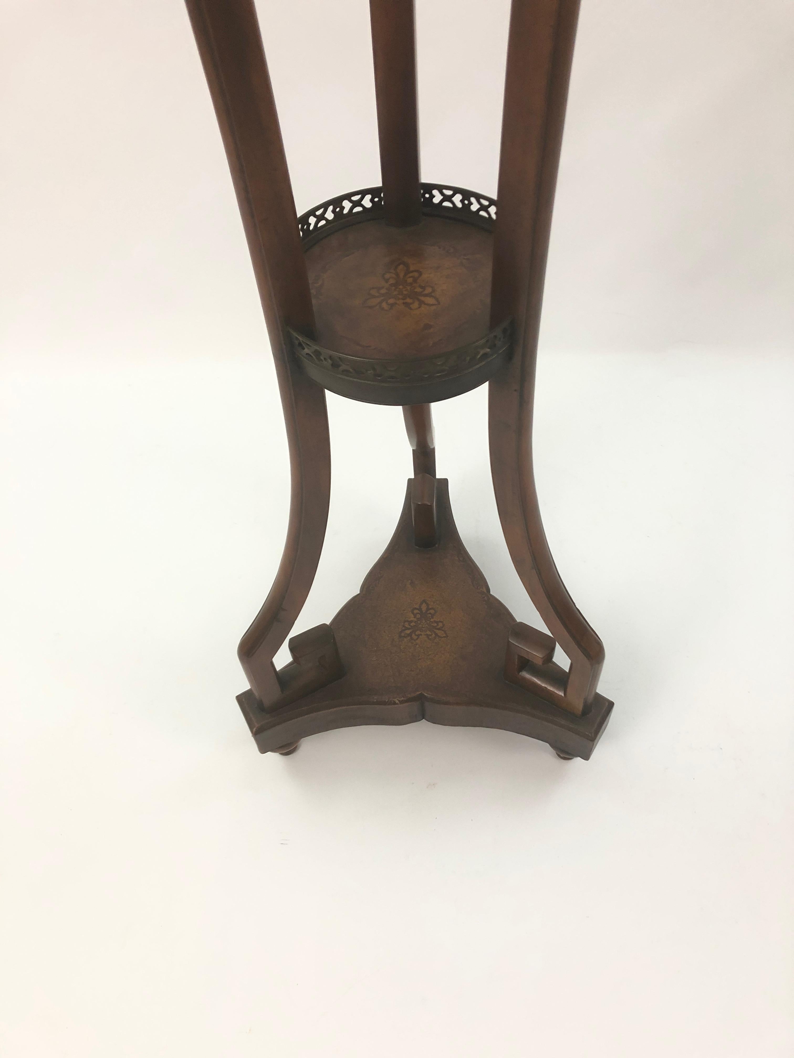 Handsome elongated mahogany stand having a marble round top with brass gallery and tooled leather lower tier with stunning Greek key inspired supports.
Bottom is 15 diameter
Top is 12.25 diameter.