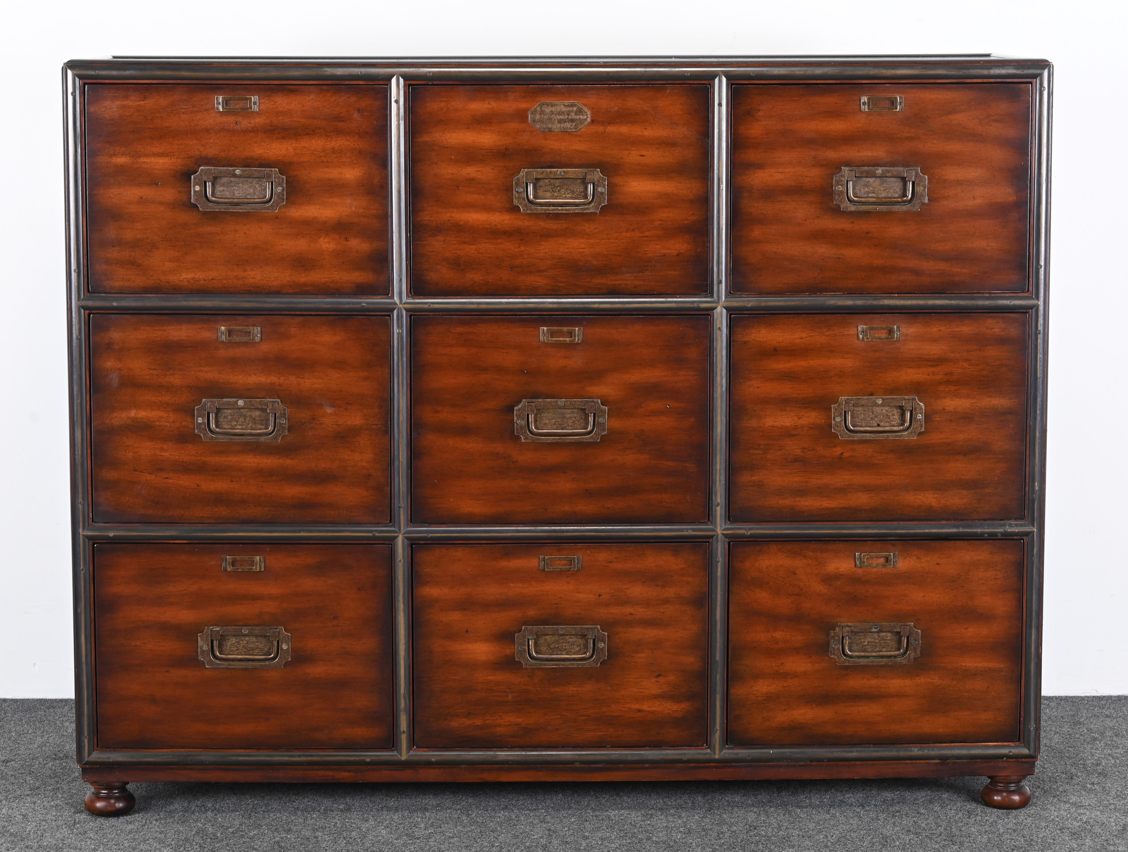 A Theodore Alexander Campaign-style Acacia solid brass finish. The chest or filing cabinet has a 9-drawer chest of drawers on bun feet.  Brass file hangers are included. This walnut veneer chest imitates the original Victorian design from the turn