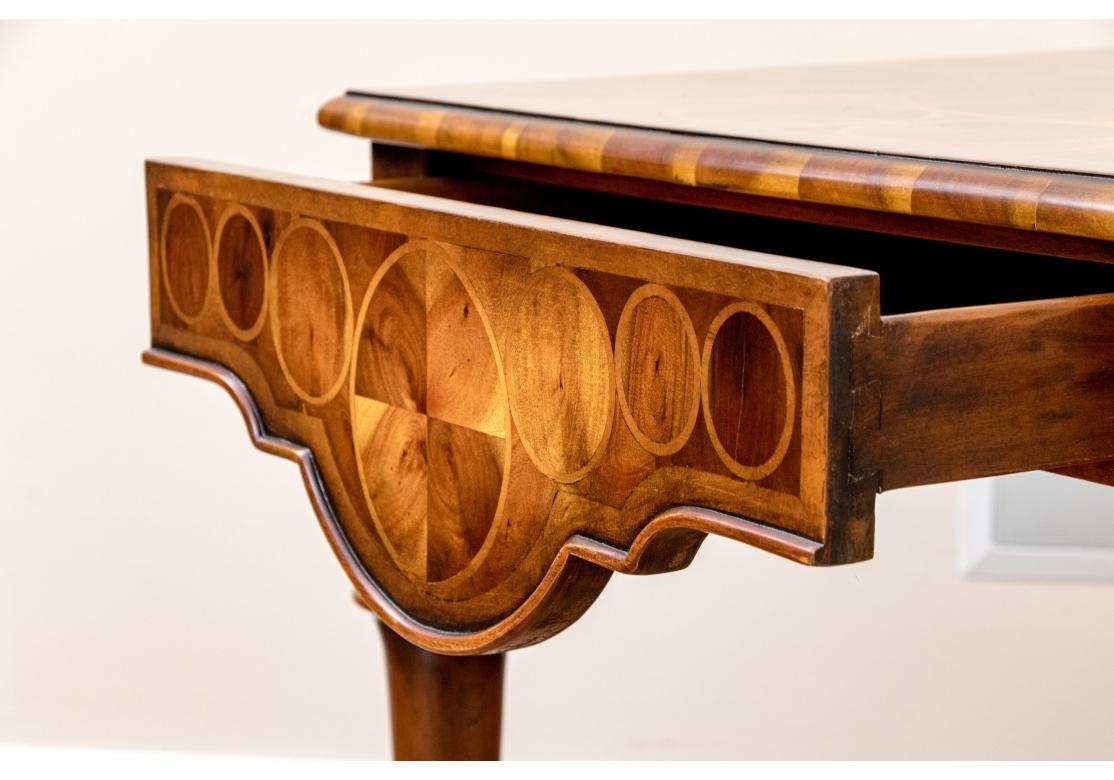 Lampe d'appoint de style anglais William and Mary comprenant un tiroir à frise façonnée, quatre pieds en trompette reliés par un étirement en forme de X surmonté d'un épi de faîtage en bois. La table est habilement marquetée de motifs géométriques