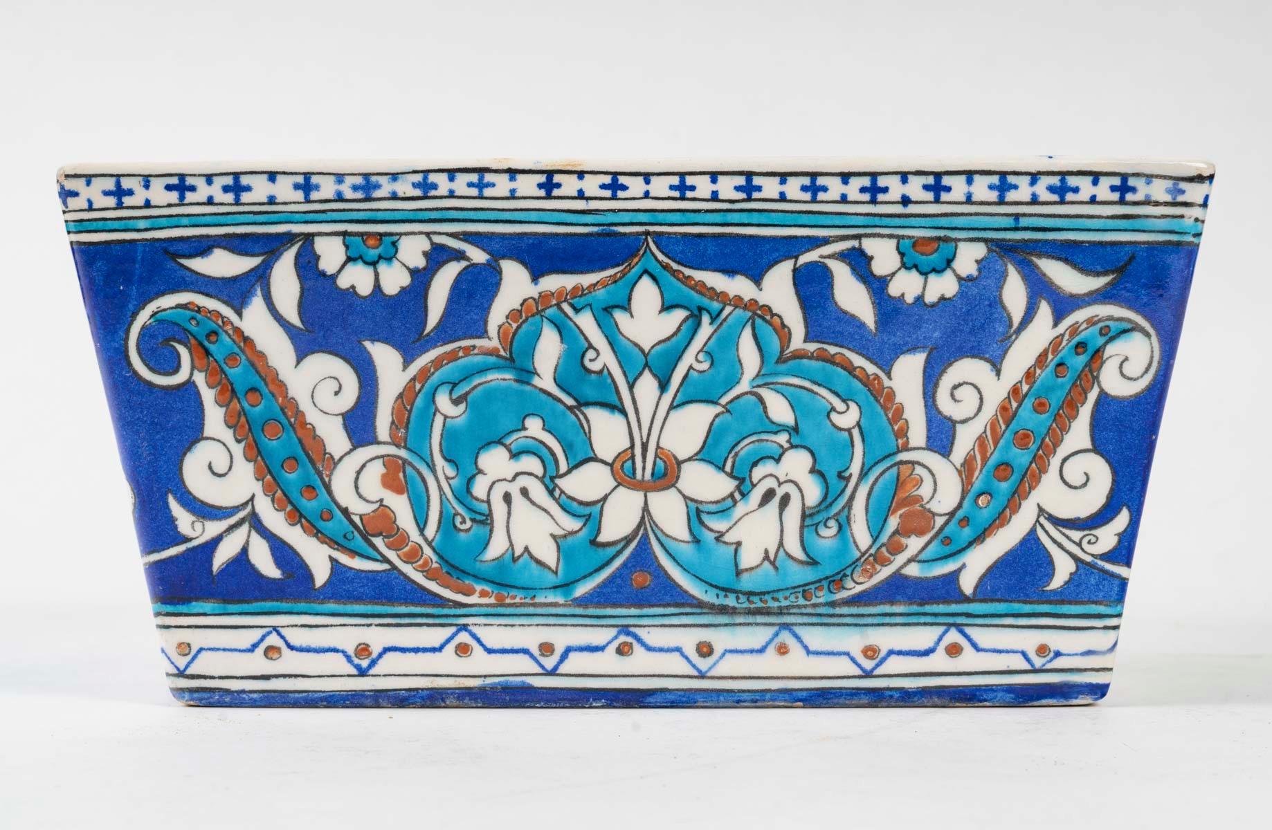Theodore Deck (1823 - 1891)
An Iznik Style Enameled Faïence Rectangular Jardiniere
Hand-painted with foliages, stylised leaves and flowers in turquoise, cobalt-blue and red outlined in black against an alternating turquoise and cobalt-blue