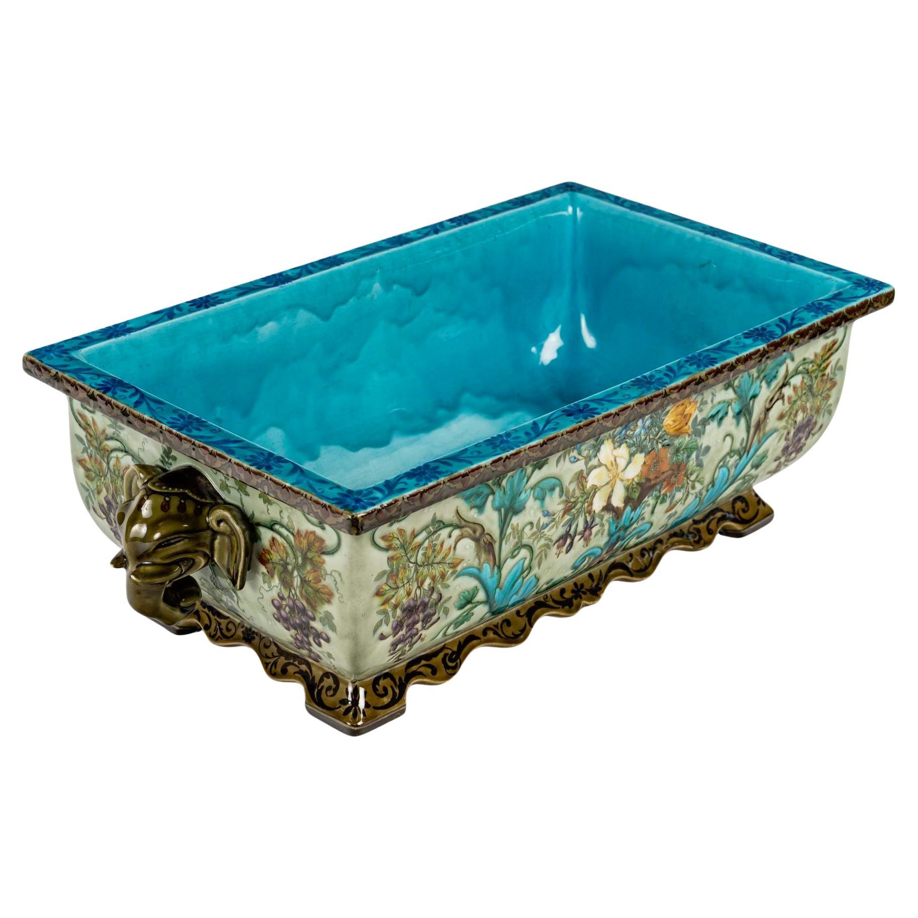 Impresionante jardinera de elefantes de loza de Theodore Deck (1823-1891)

De forma rectangular flanqueada por dos asas con cabeza de elefante, el fondo exterior de celadón está pintado en todo su contorno con follajes, frutas y volutas,
Rarísimo y