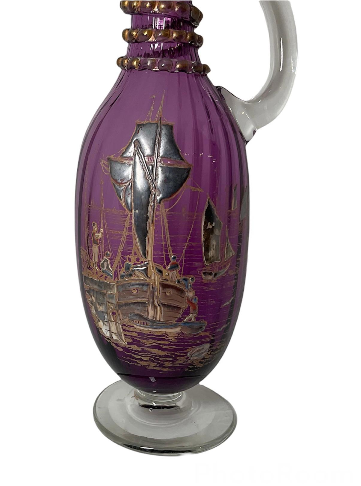 This is a rare Theodore Rossler purple glass wine decanter with large C-Shaped clear crystal handle following the “Color Cake” enamel technique. It depicts what appear to be an Asian scene of a Chinese Junk ship and boats with some fishermen in the
