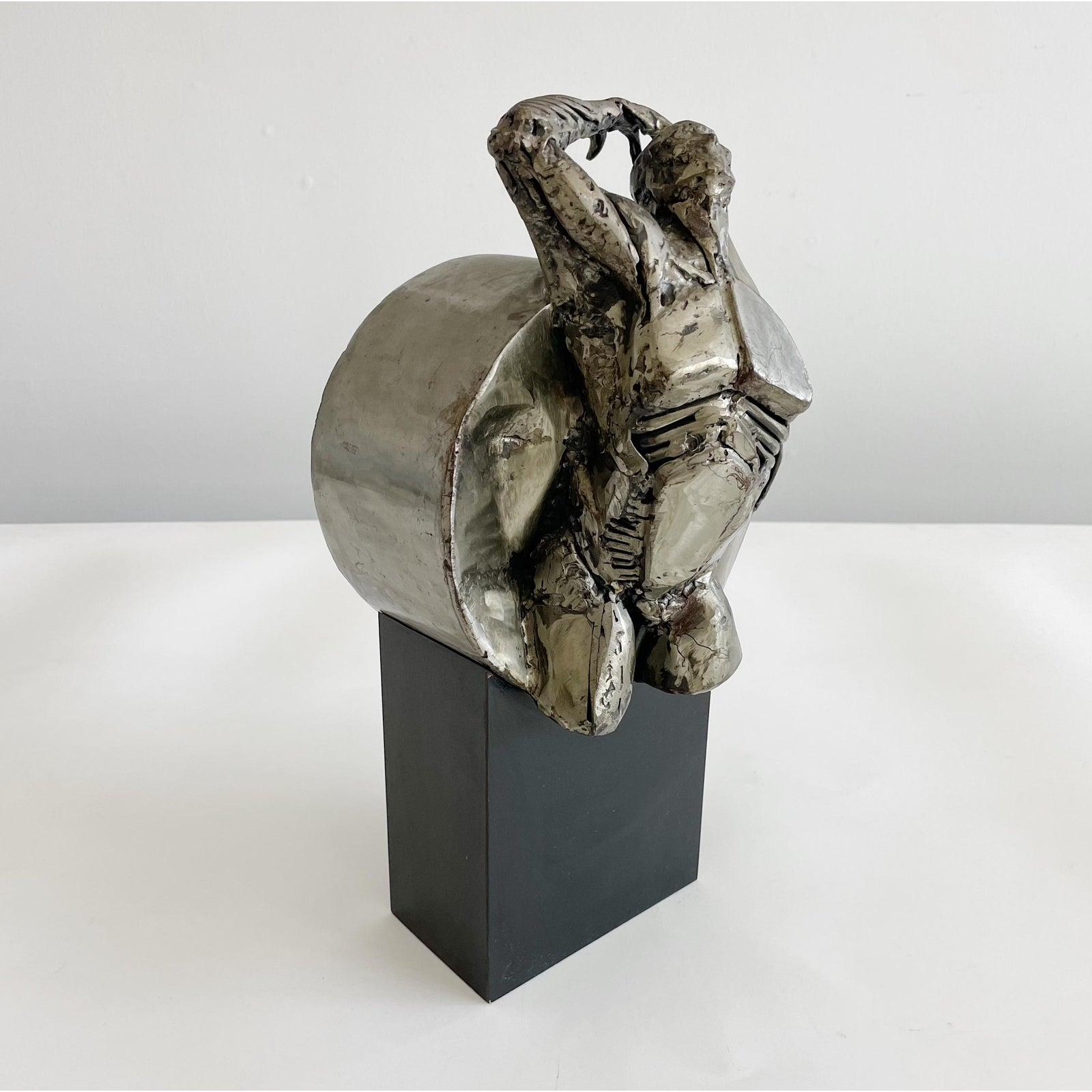 Figurale Skulptur des Künstlers Ted Gall aus Stahl, befestigt auf einem Sockel aus schwarzem Schichtholz. Unterschrieben.

Theodore T. Gall begann seine künstlerische Laufbahn Mitte der sechziger Jahre als Animator für Lehrfilme und erweiterte