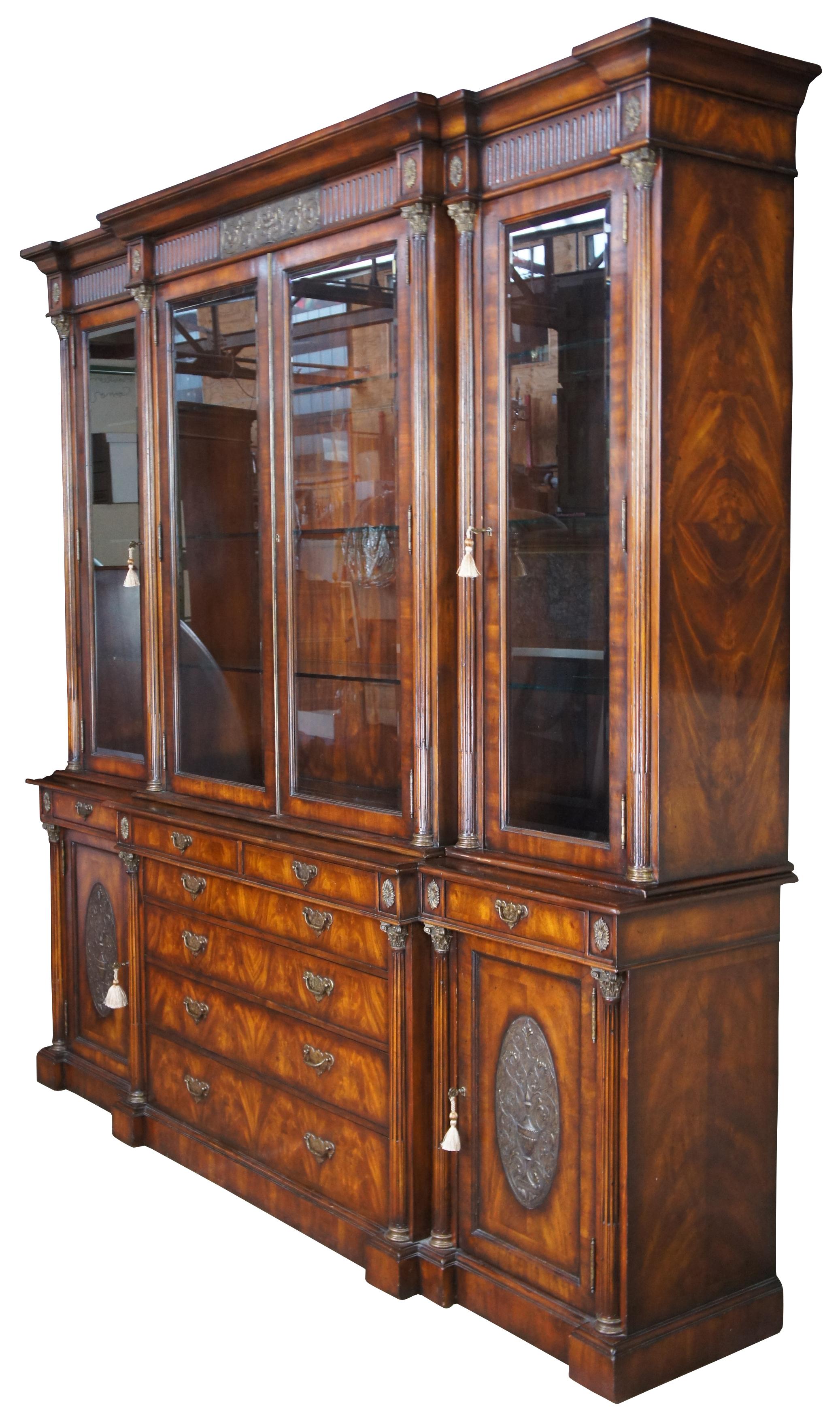 Monumental Regency/Neoclassical inspired breakfront by Theodore Alexander. Made from flame/ crotch mahogany with brass hardware. Features a doric crown with triglyph frieze over long carved columns, intricate capitals, medallions and low relief