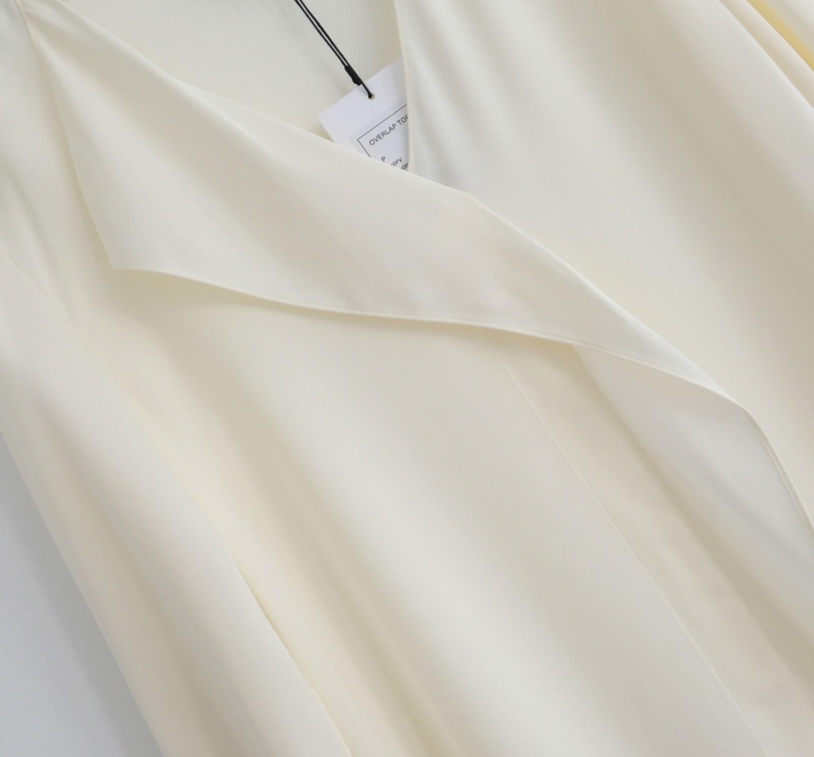 Clásica y atemporal blusa de seda superpuesta Theory. Nuevo con etiquetas. Confeccionado en crepé de chine de seda color crema, tiene un corte fluido relajado con detalles delanteros drapeados y puños con aberturas. Sin cierres. Talla P/XS-S y.