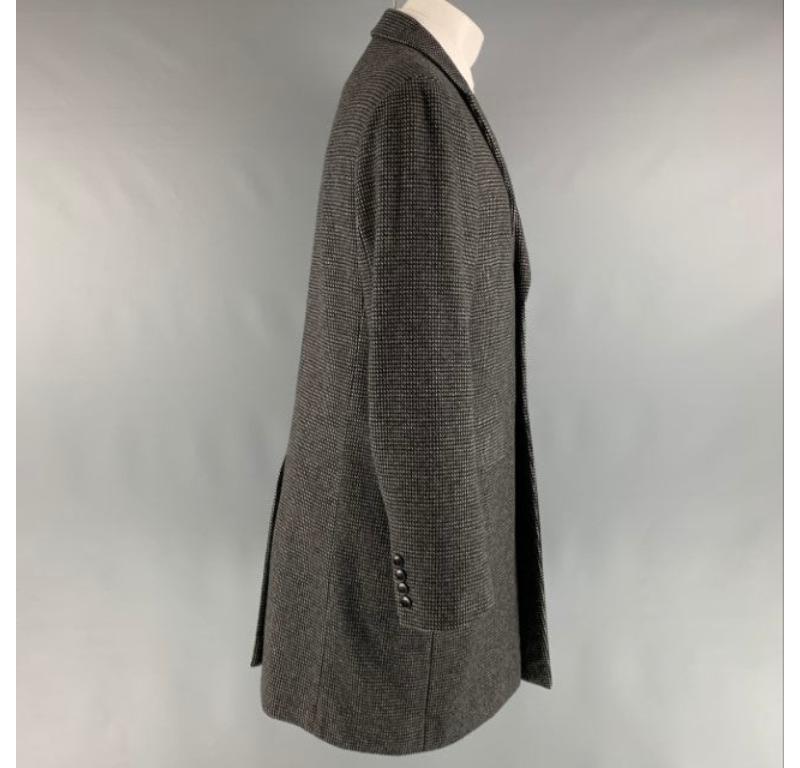 THEORY coat comes in a black and grey wool and cashmere woven material with a full liner featuring a peak lapel, flap pockets, single back vent, and a button closure.Very Good Pre-Owned Condition. Minor mark at left panel. 

Marked:  M