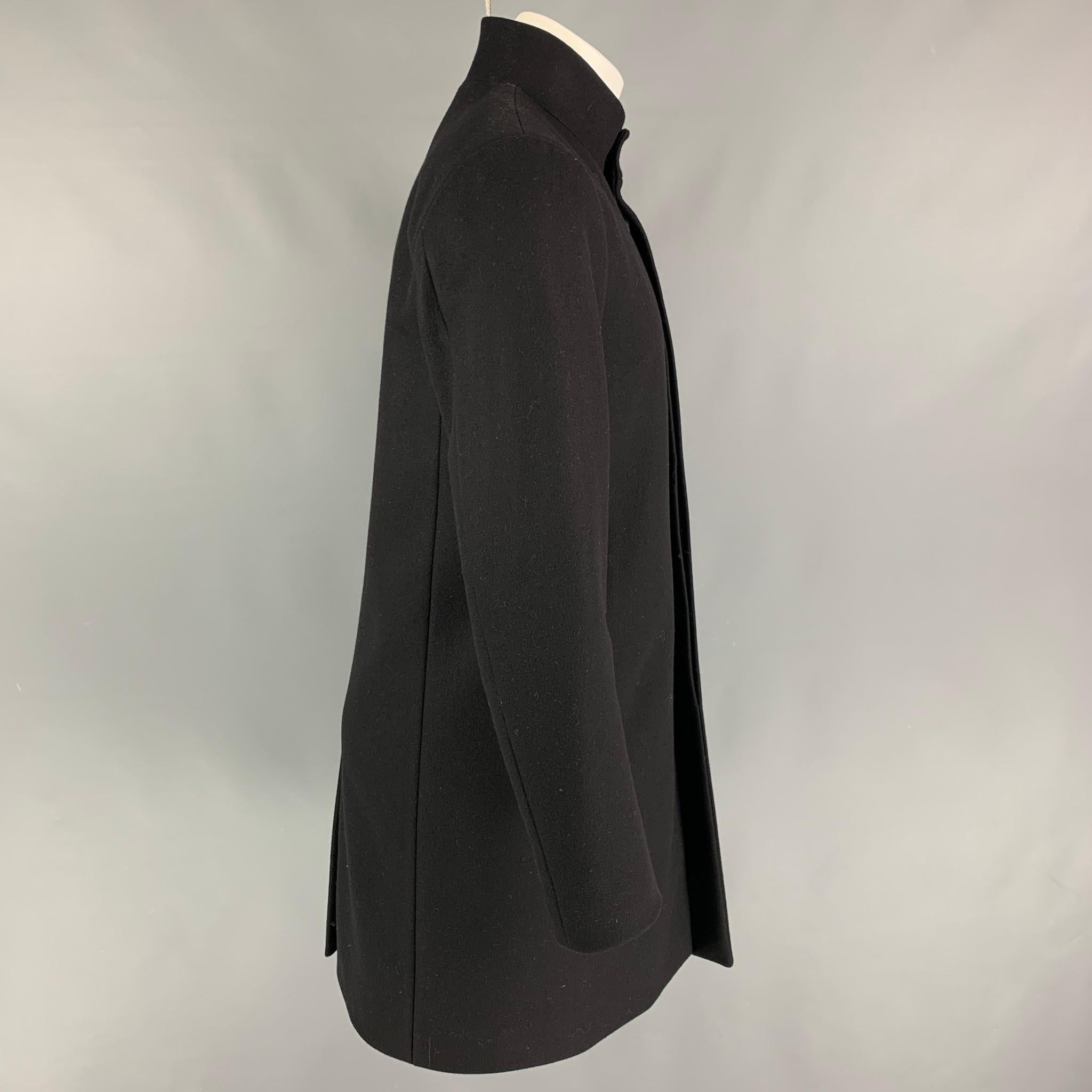 THEORY coat comes in a black wool blend with a full liner featuring a stand up collar, slit pockets, single back vent, and a hidden button closure. 

Very Good Pre-Owned Condition.
Marked: M
Original Retail Price: $849.00

Measurements:

Shoulder: