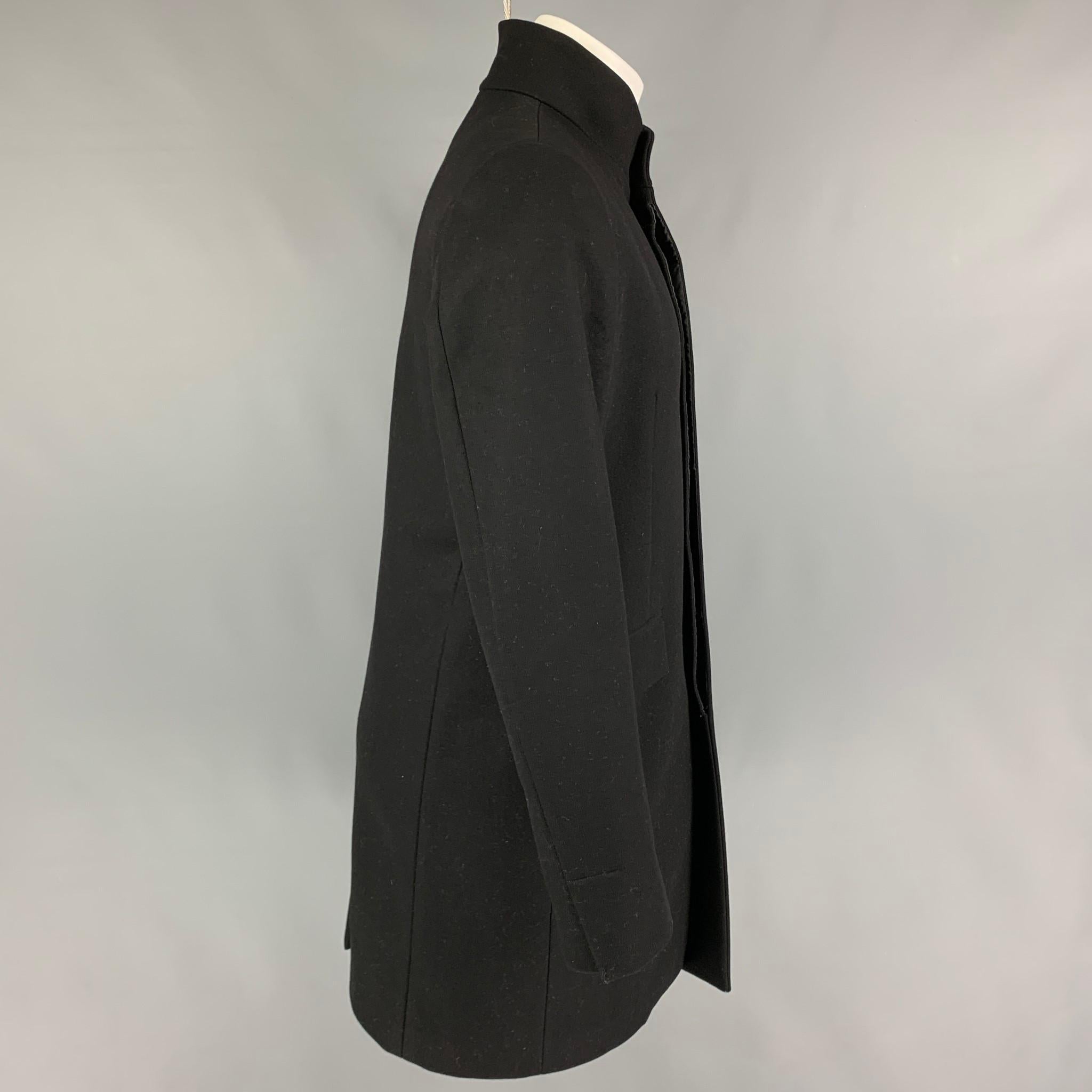 THEORY coat comes in a black wool blend featuring flap pockets, single back vent, and a hidden placket closure. 

Very Good Pre-Owned Condition.
Marked: M

Measurements:

Shoulder: 17.5 in.
Chest: 43 in.
Sleeve: 26.5 in.
Length: 36 in. 