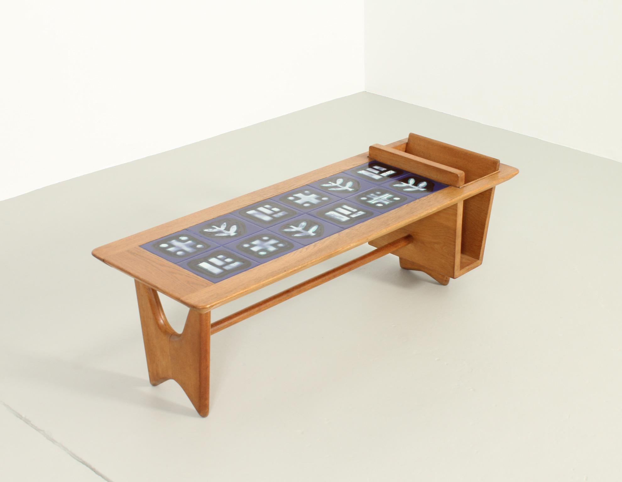 Coffee table model Thibault designed in 1960 by Robert Guillerme and Jacques Chambron for Votre Maison, France. Solid oak wood and ceramic tiles by Boleslaw Danikowski with magazine rack on one side.