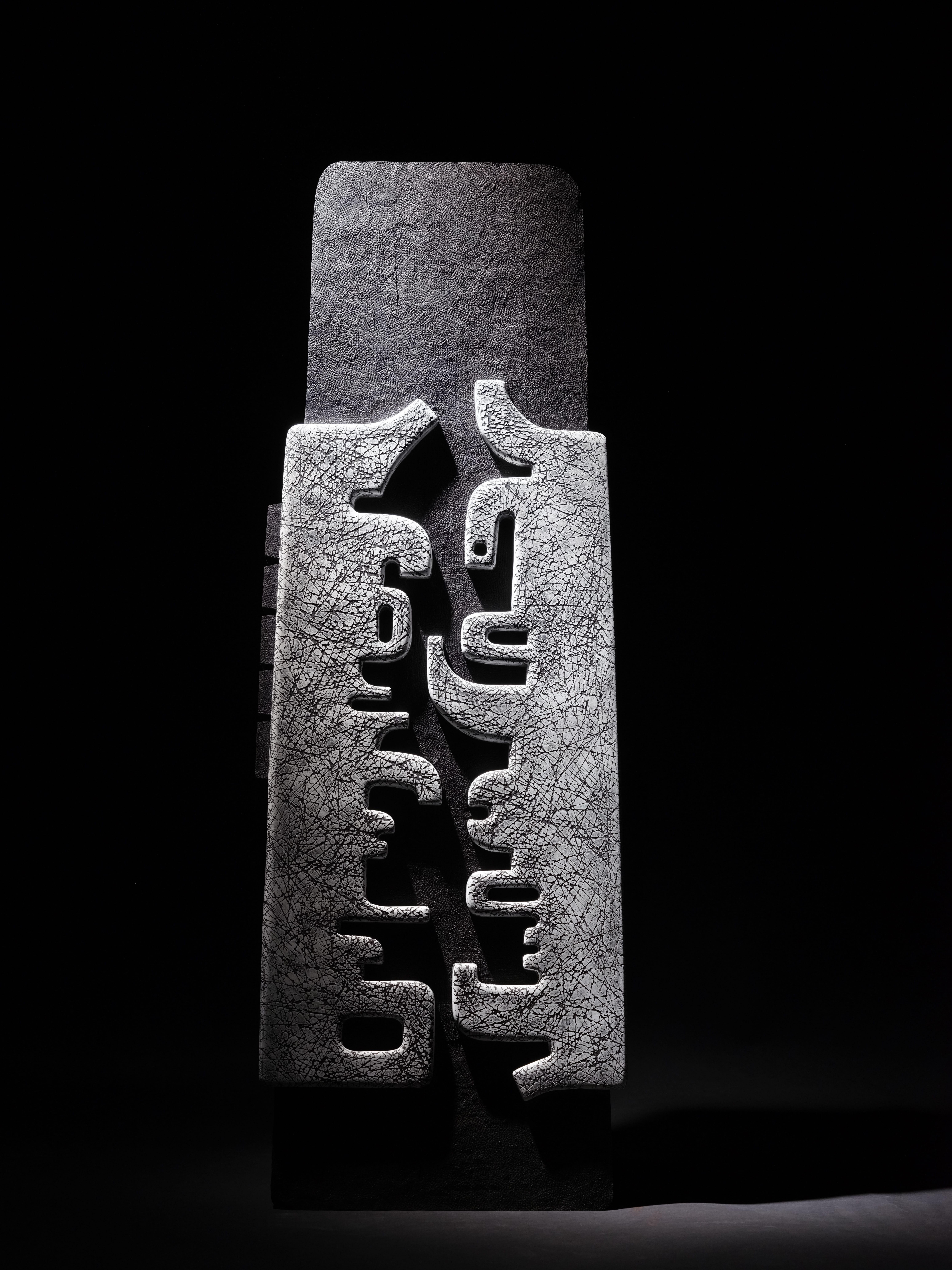 No.201125 an abstract sculpture in wood by French sculptor Thierry Martenon. Walnut wood, India ink patina, 35.4 x 13 x 5.9 inches (90 × 33 × 15 cm).
This piece, with its marked verticality and symbolic motifs, is reminiscent of the aesthetics of