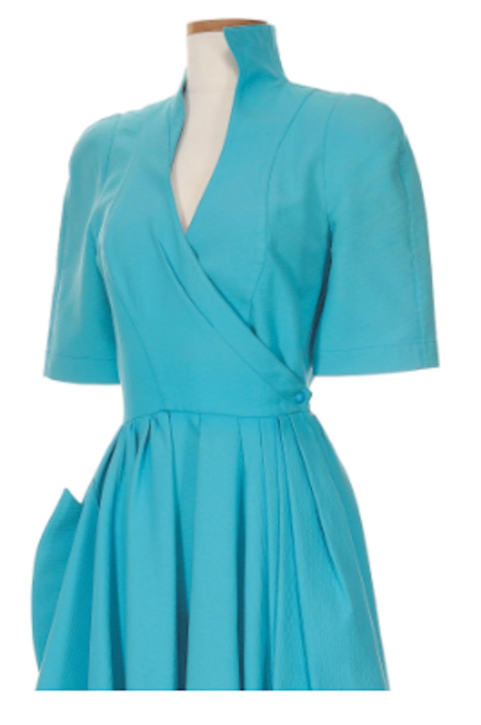 Thierry Mugler Aqua Blue Wrap Dress 1980's. Electric blue cotton pique wrap dress with iconic Mugler details including the pointed pocket, wave-like neckline and high-low collar. A stunning and collectible dress from the house of Mulger.
- Snap