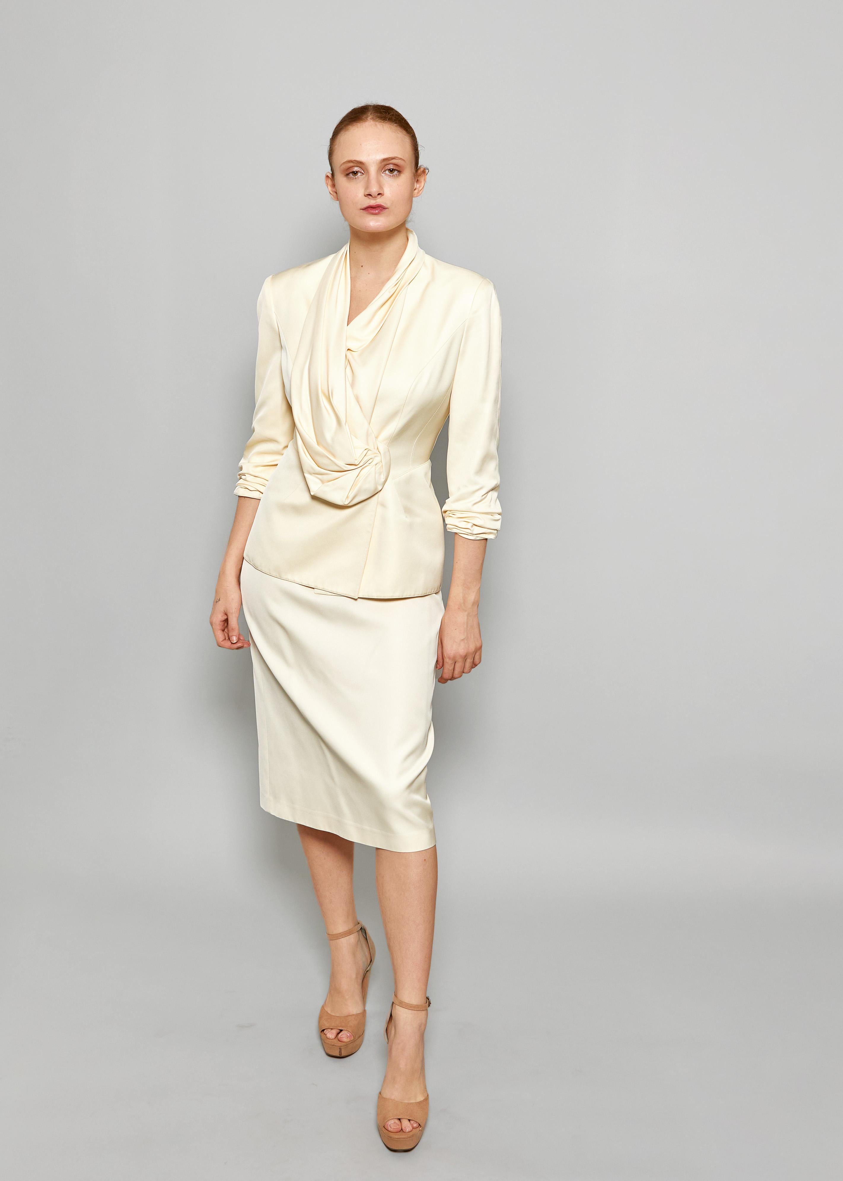 Elevate your timeless style with our Thierry Mugler 1990's Cream Skirt Suit. With its ruched draped blazer and creamy hue, this suit exudes elegance and sophistication. Perfect for any occasion, it will add a touch of luxury to your