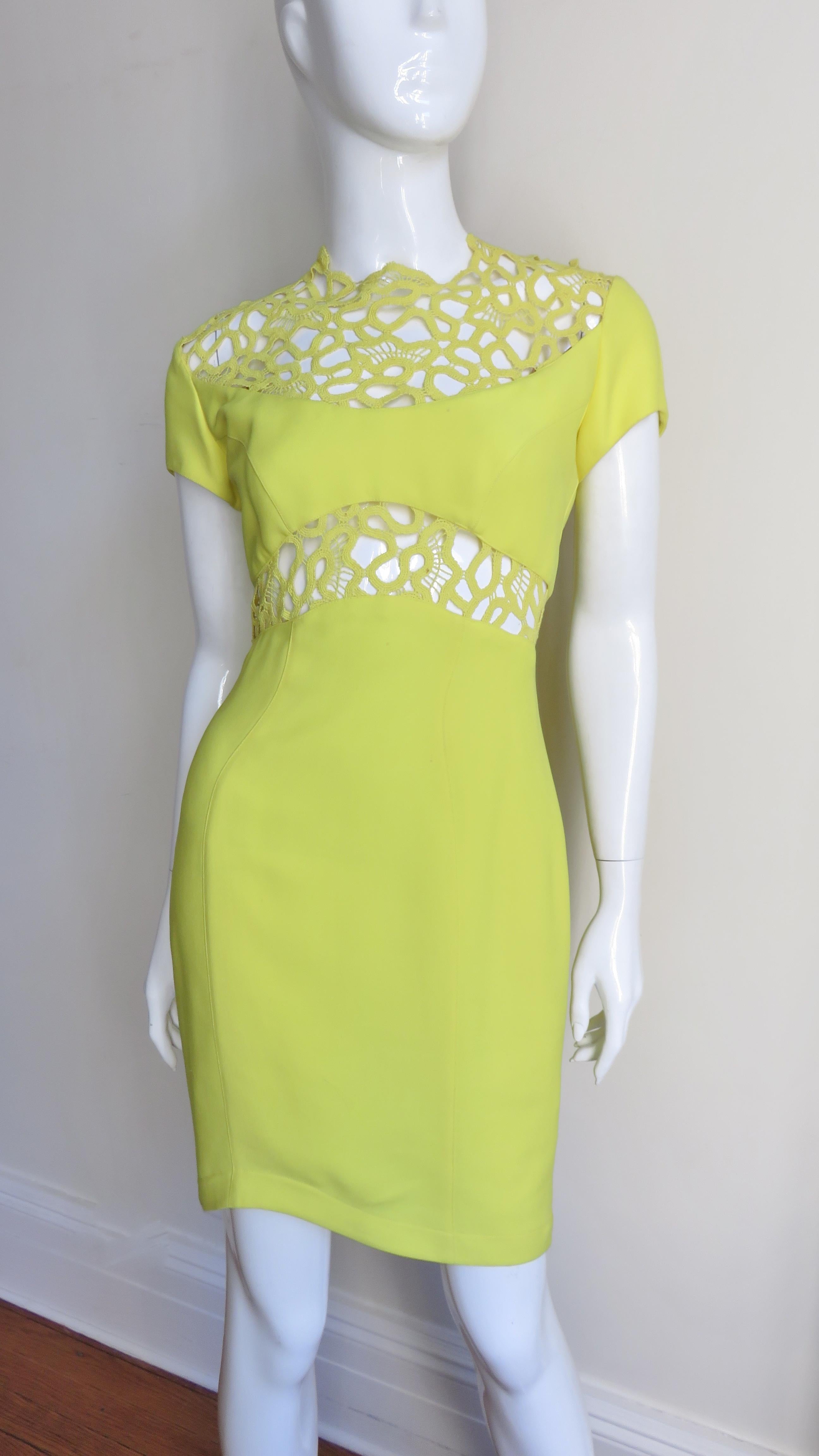 A stunning brilliant yellow silk bodycon dress from Thierry Mugler.  It has short sleeves and is fitted through to the asymmetric hemline.  The upper chest, upper back and midriff are intricately detailed in matching airy macrame/lace patter.  It is