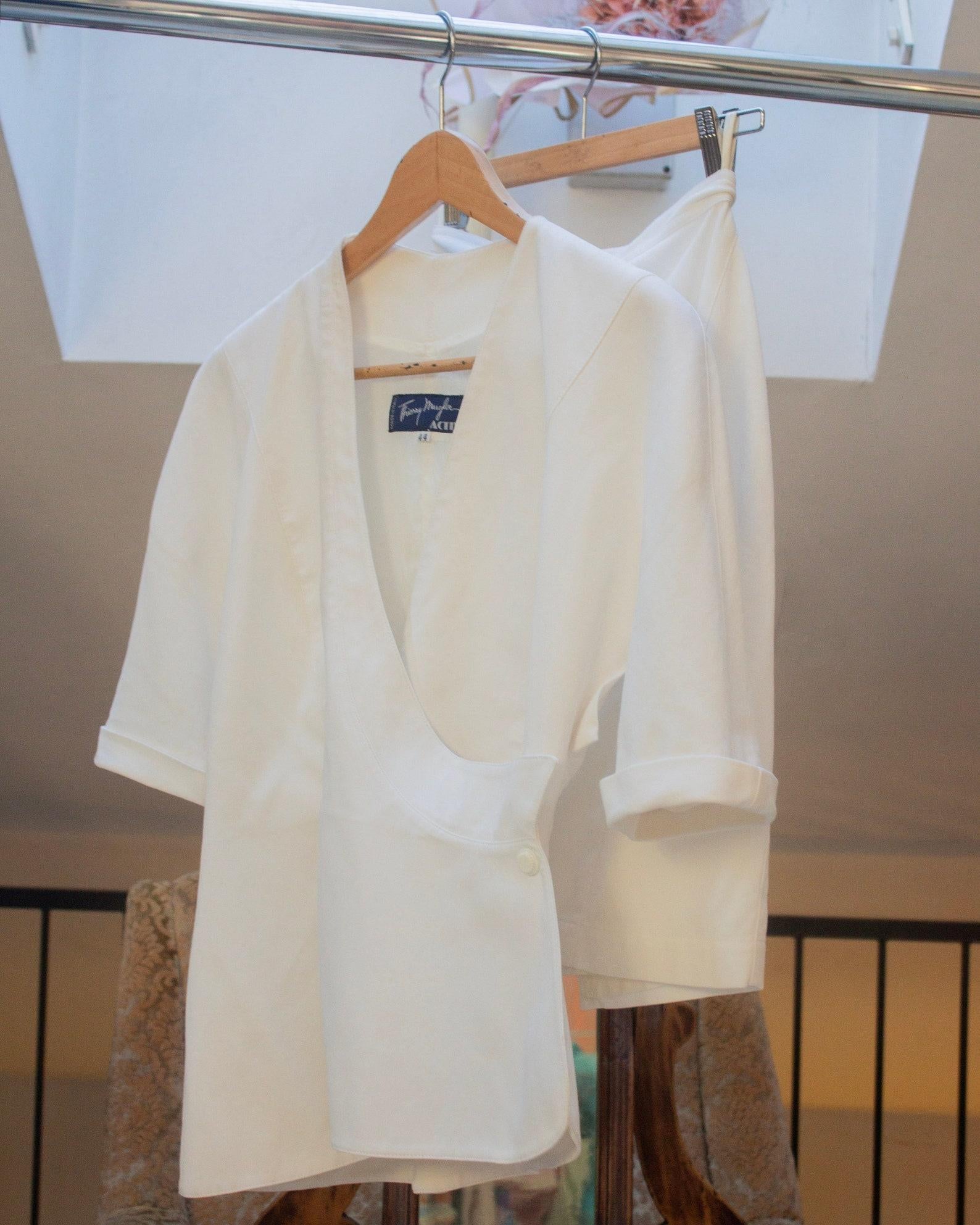 Thierry Mugler Activ début des années 90 tailleur jupe dramatique en coton blanc avec col V profond, veste architecturale en sablier et mini jupe crayon (S)
La veste et la jupe sont entièrement doublées 
Veste ajustée en forme de sablier 
100%
