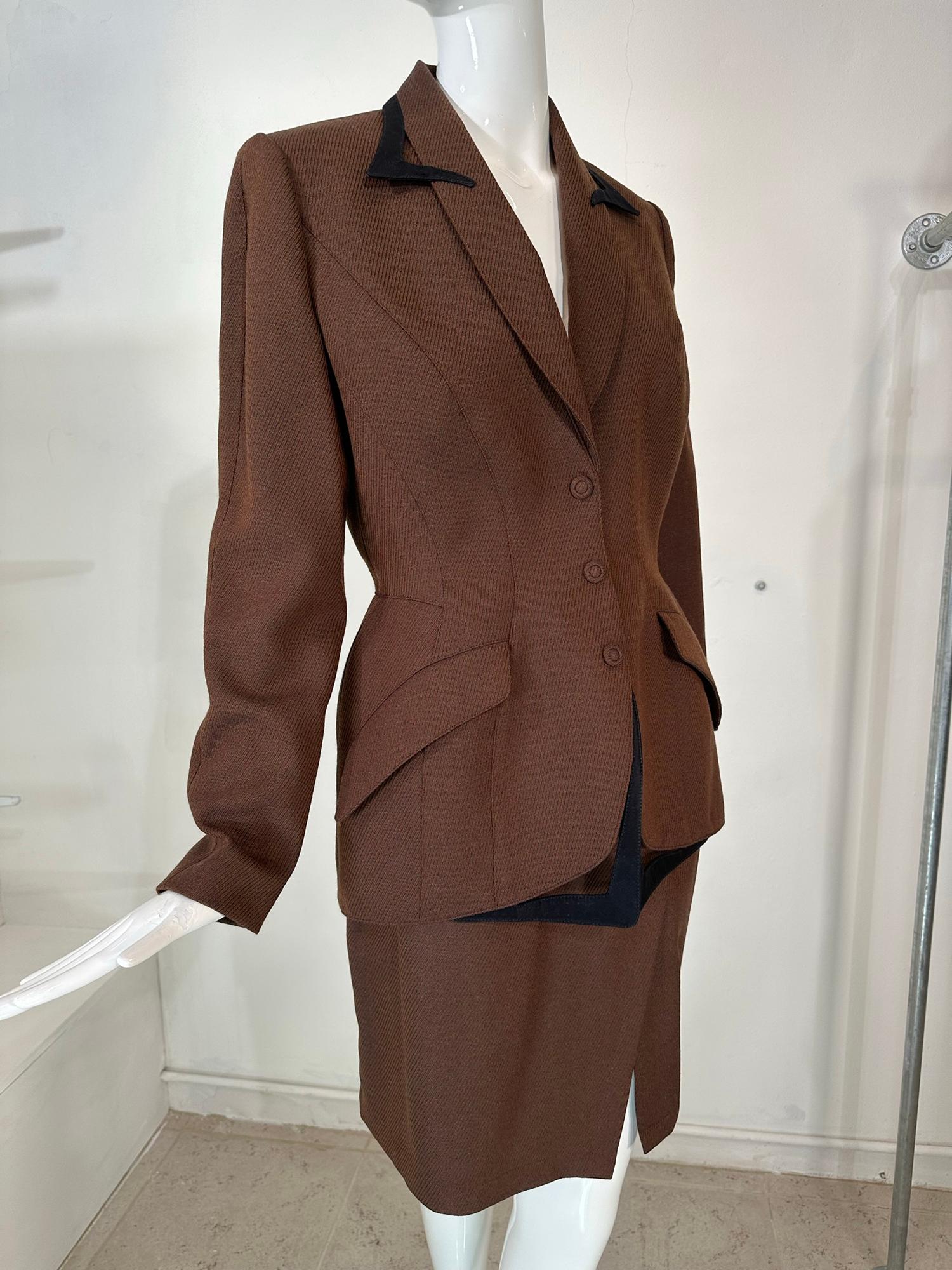 Thierry Mugler brown wool twill suit from the 1980s. Princess seam, single breasted jacket is fitted through the waist and hugs the hips. This beautifully tailored jacket has exaggerated angled hip flap pockets & closes at the front with covered