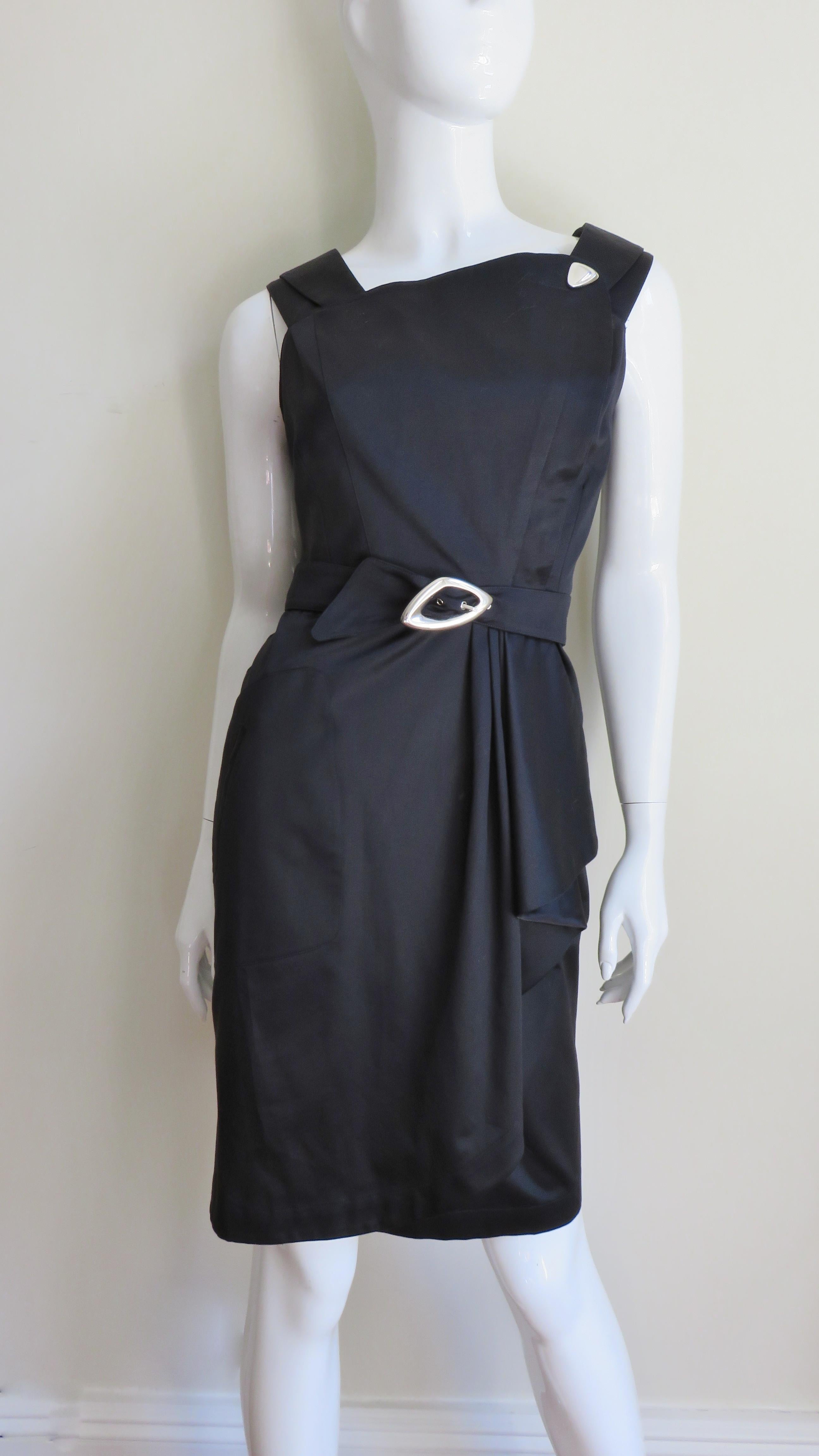 An great rich black cotton dress from Thierry Mugler.  It is sleeveless with an asymmetric neckline accented with silver hardware at one side.   It has a matching belt with a silver buckle and the wrap skirt is straight with draping at one hip. It