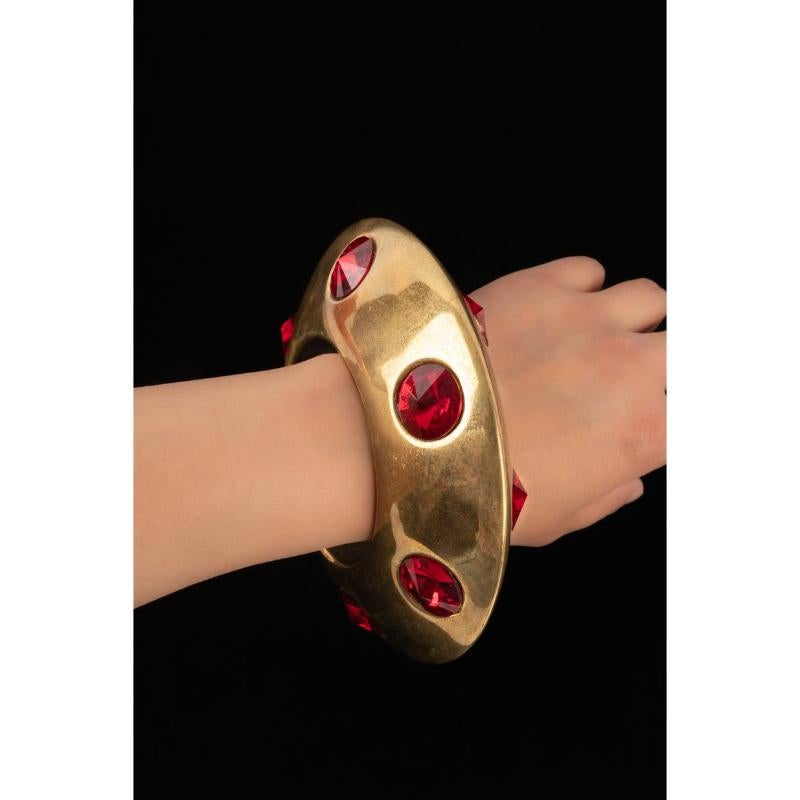 Thierry Mugler - Golden metal bracelet with red rhinestones. Jewellery from the 1990s.

Additional information:
Condition: Good condition
Dimensions: Circumference: 19.5 cm - Diameter: 6.2 cm
Period: 20th Century

Seller Reference: BRA51