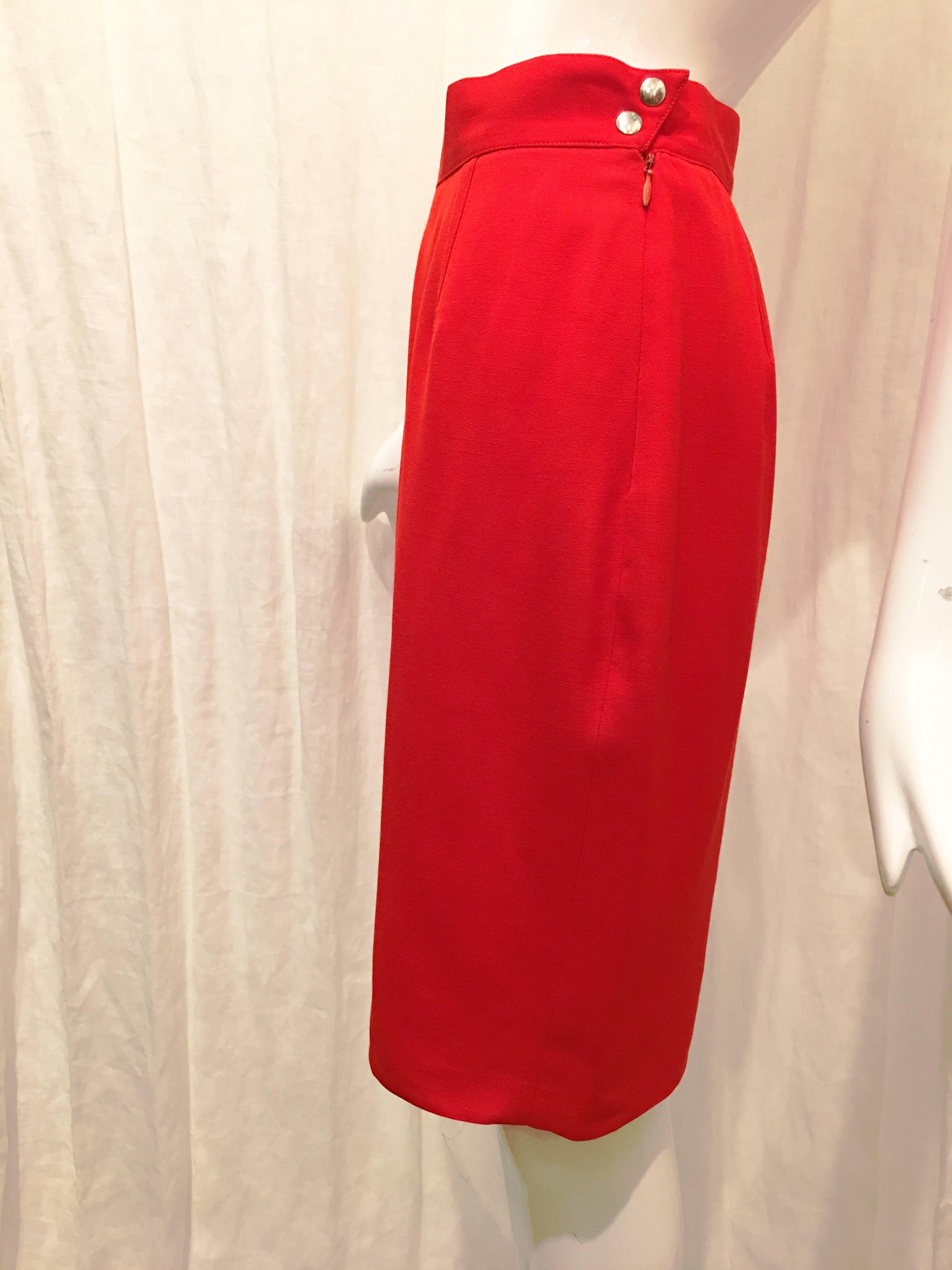 Thierry Mugler red wool pencil skirt. Two snap buttons as well as zipper at left side of garment. Sharp pointed edge at buttons adds a subtle hint of edginess to an otherwise very simple garment. Hits at the knee. Fully lined. 
A simple staple skirt