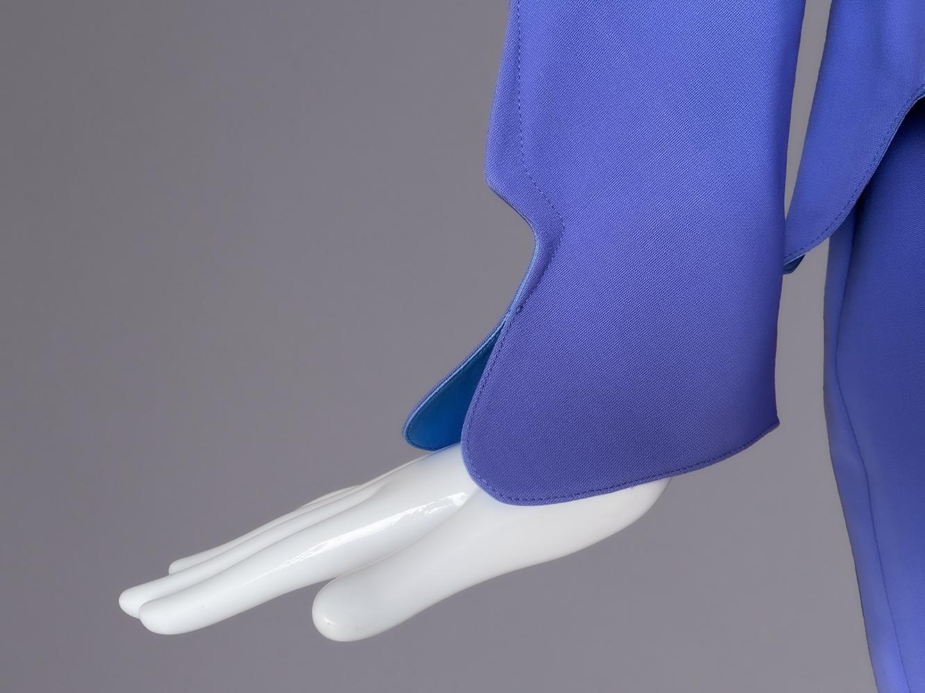 In questo tailleur con gonna di Thierry Mugler del 1997, si assiste a una masterclass di seduzione scultorea in cui la precisione sartoriale si scontra con la fantasia.
Bellissimo ensemble color pervinca, che esemplifica l'approccio architettonico