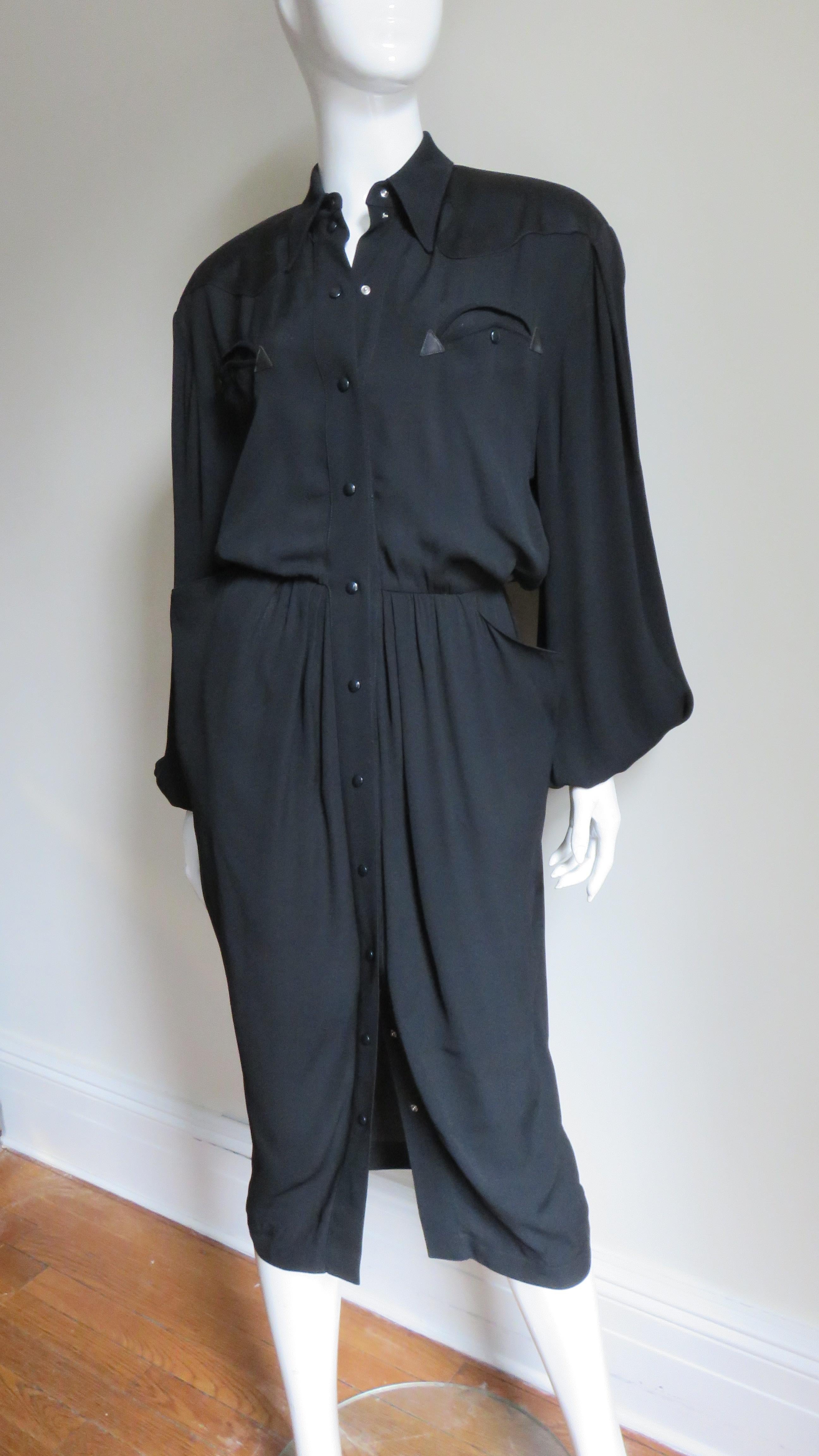 A fabulous black dress from Thierry Mugler with lots a great detail.  It has a shirt collar, curved chest pockets, balloon sleeves with curved cuffs, and light shoulder pads.  There are rounded yokes front and back.  The bodice is blouson and