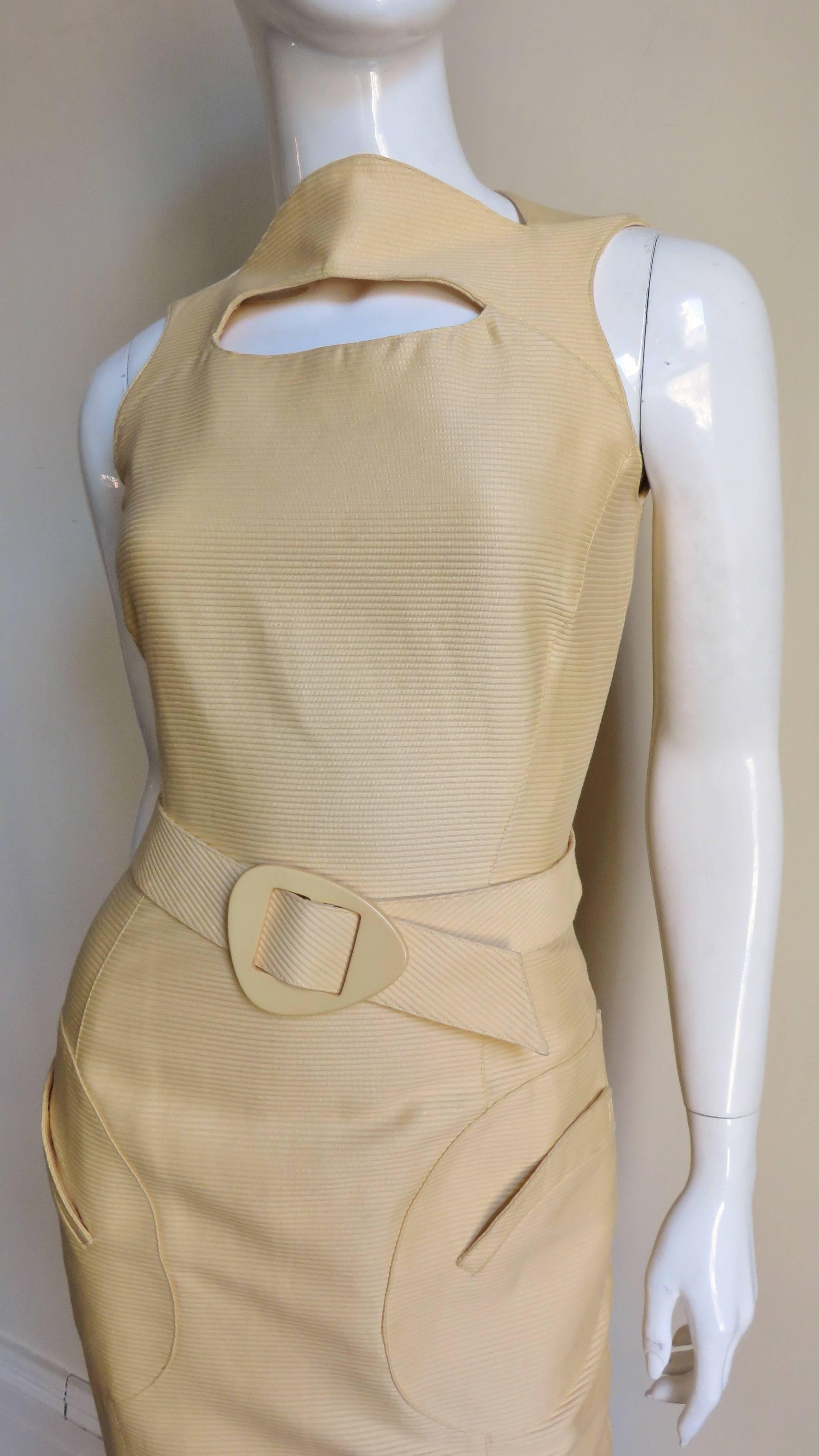 Ein buttergelbes Seidenkleid von Thierry Mugler.  Es hat einen Bateau-Ausschnitt mit einem ovalen Ausschnitt darunter, Prinzessnähte für eine gute Passform und 2 aufgesetzte Taschen vorne. Das Kleid wird mit einem passenden Gürtel mit gelber