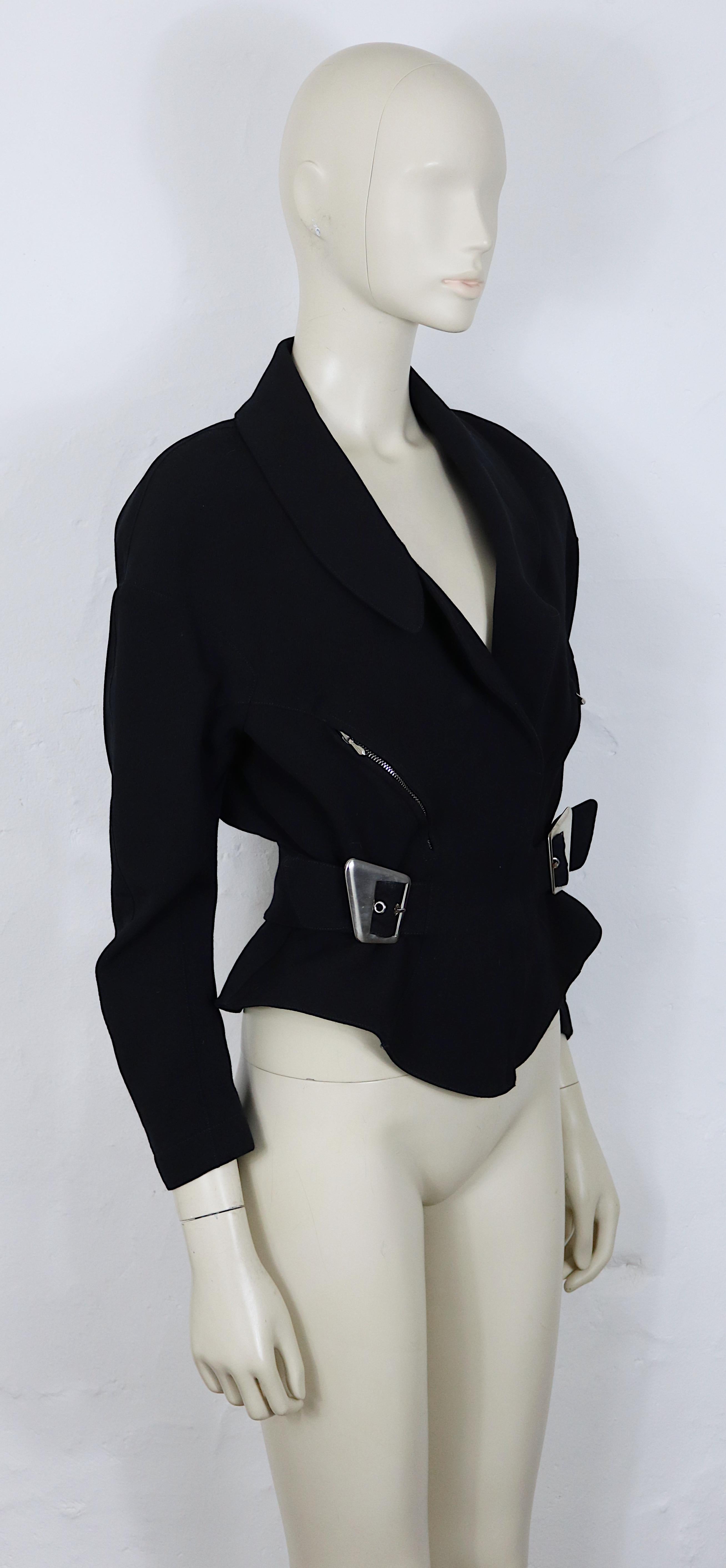 Giacca peplo in lana pettinata nera vintage di Thierry Mugler con struttura morbida.

Questa giacca è caratterizzata da:
-  Una profonda scollatura a V e ampi revers che creano un effetto drammatico e allungato.
- Due fibbie in argento spazzolato in