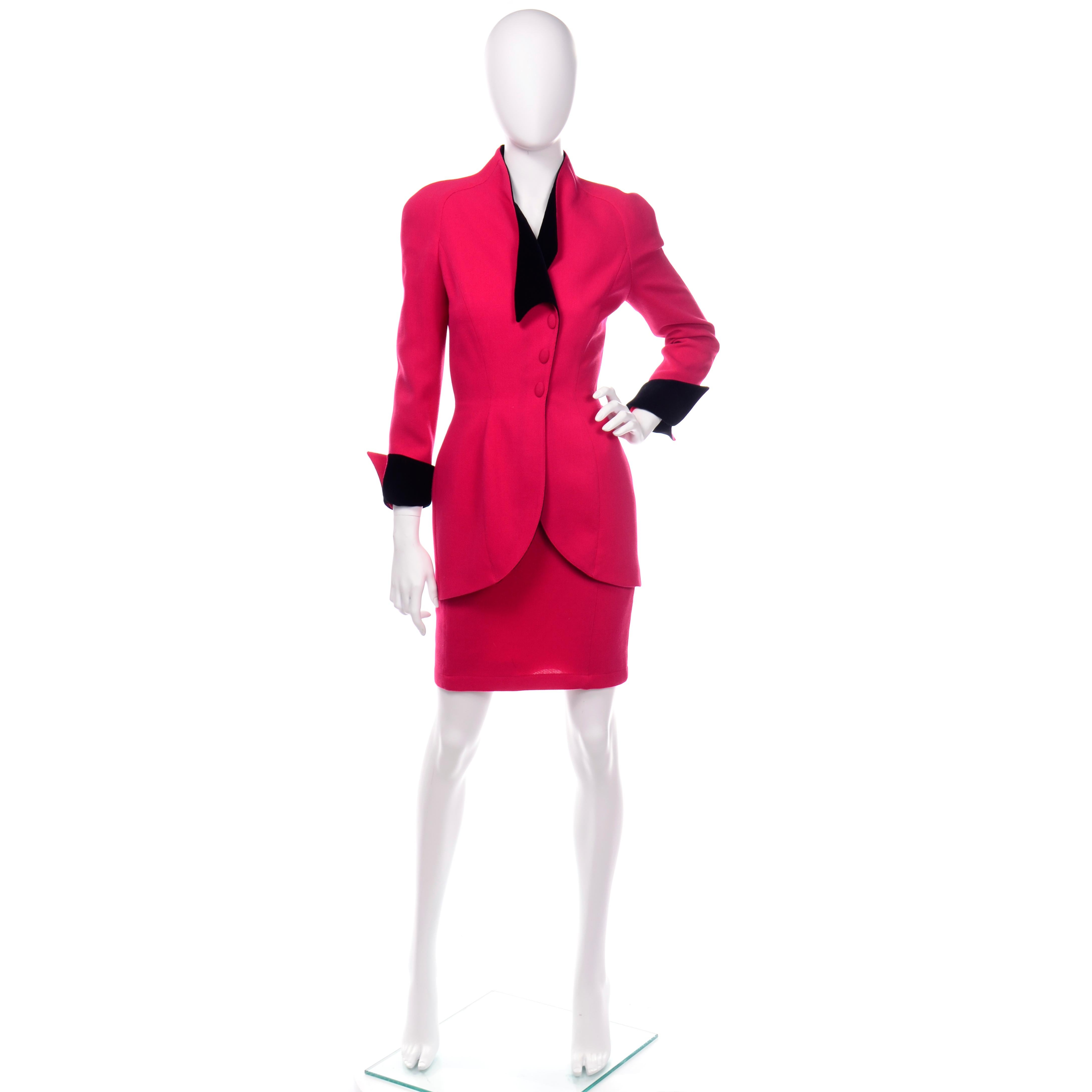 This is a fabulous vintage Thierry Mugler 2 piece skirt suit with a cinched waist blazer and a slim pencil skirt. The suit is in a strawberry red wool and is lined in cotton. The jacket buttons up the front and has upturned black velvet cuffs and a