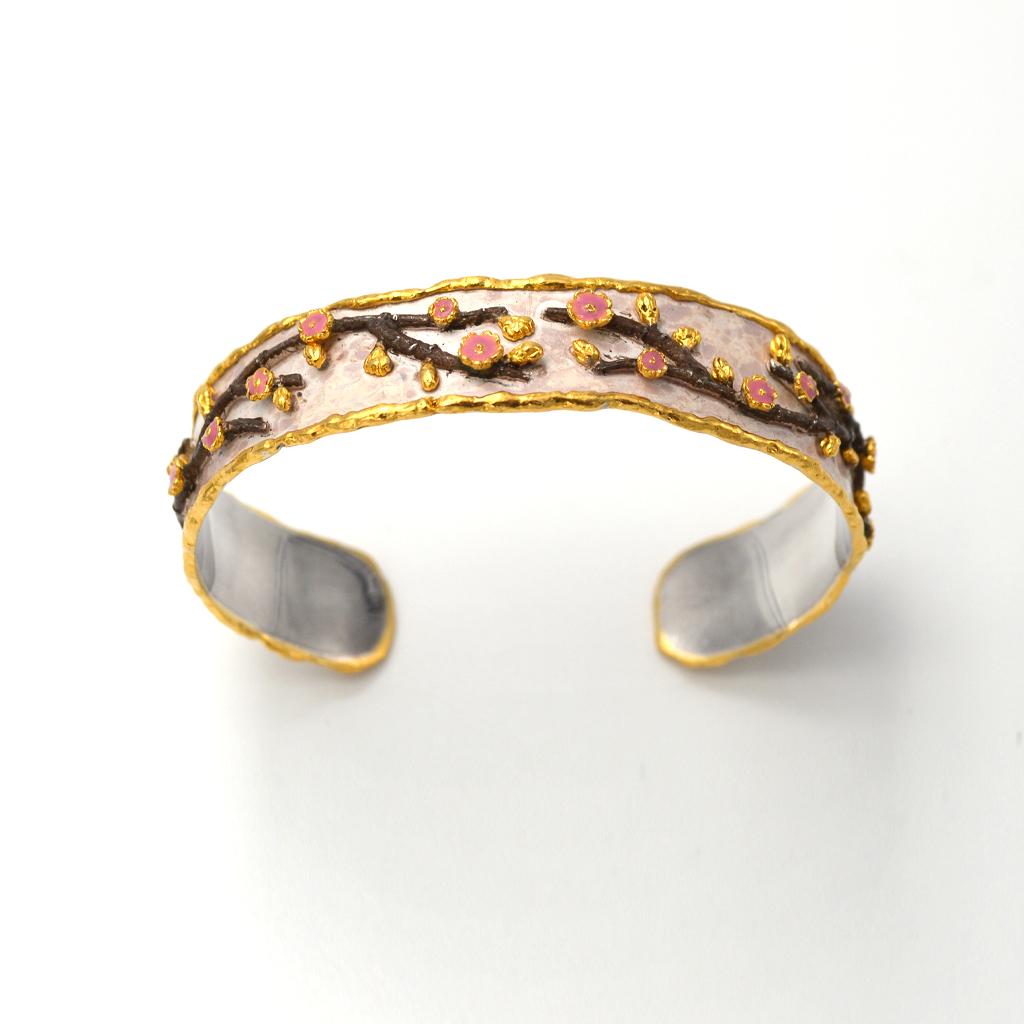 Inspired by the energy pulsating throughout nature, Velyan unites pure metals and gemstones into stunning styles that display the grandeur of fine jewelry.

This cuff bracelet features white patina and enamel to create cherry blossoms in sterling