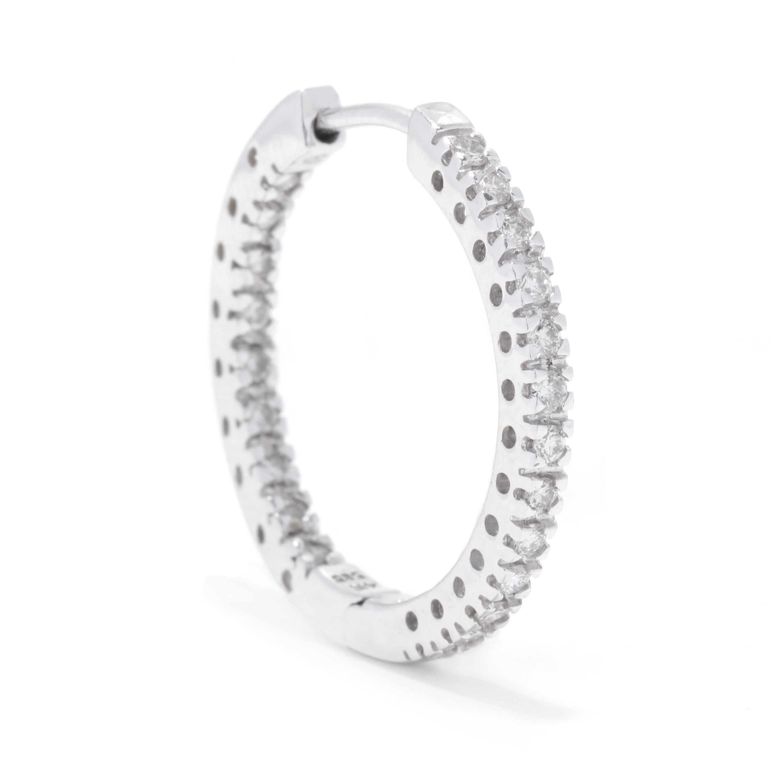 A pair of 14 karat white gold thin diamond inside outside hoop earrings. These quarter size hoops feature prong set, round brilliant cut diamonds weighing approximately 1 total carat on the outer front and inner back, and with latch back