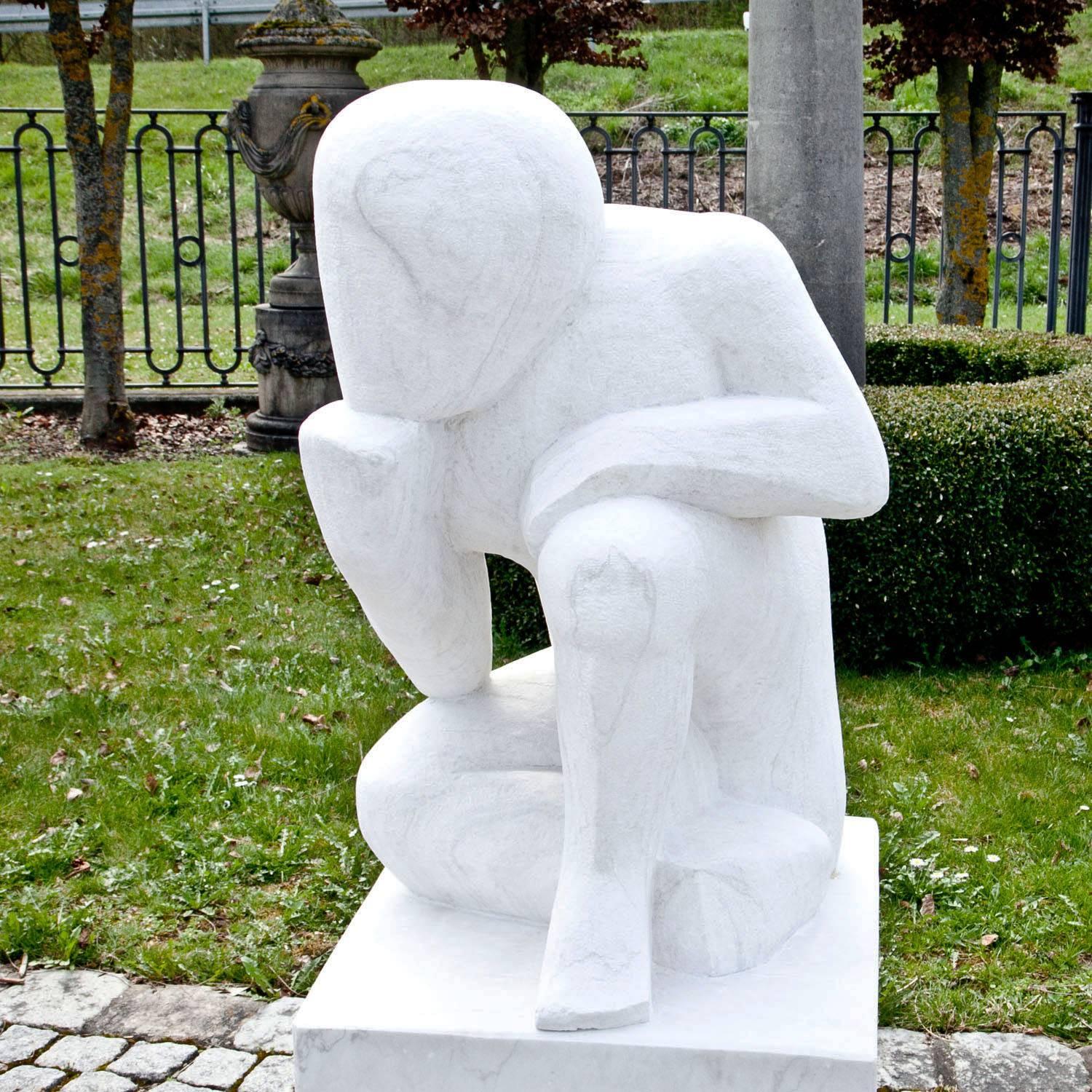 Abstract figure of a thinker, resting his head on his fist, on a square base. The sculpture was hand-carved out of white marble and has a fine surface.