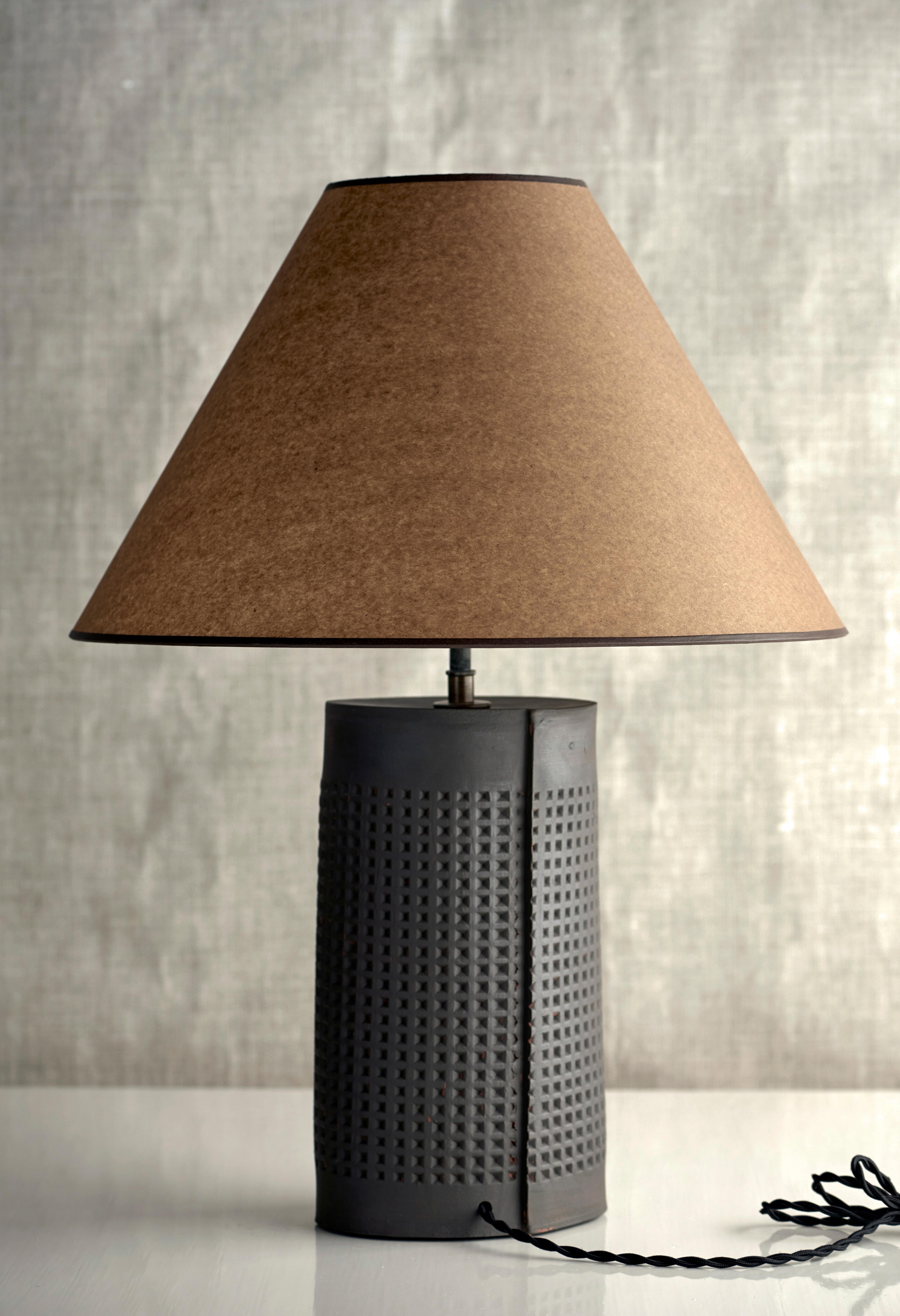 Description

Handmade stoneware slab construction. Lamps are individually crafted and one of a kind.

Finish

Matte black glaze. Antique brass fittings, dimmer switch on socket. Braided black cloth cord and Kraft paper