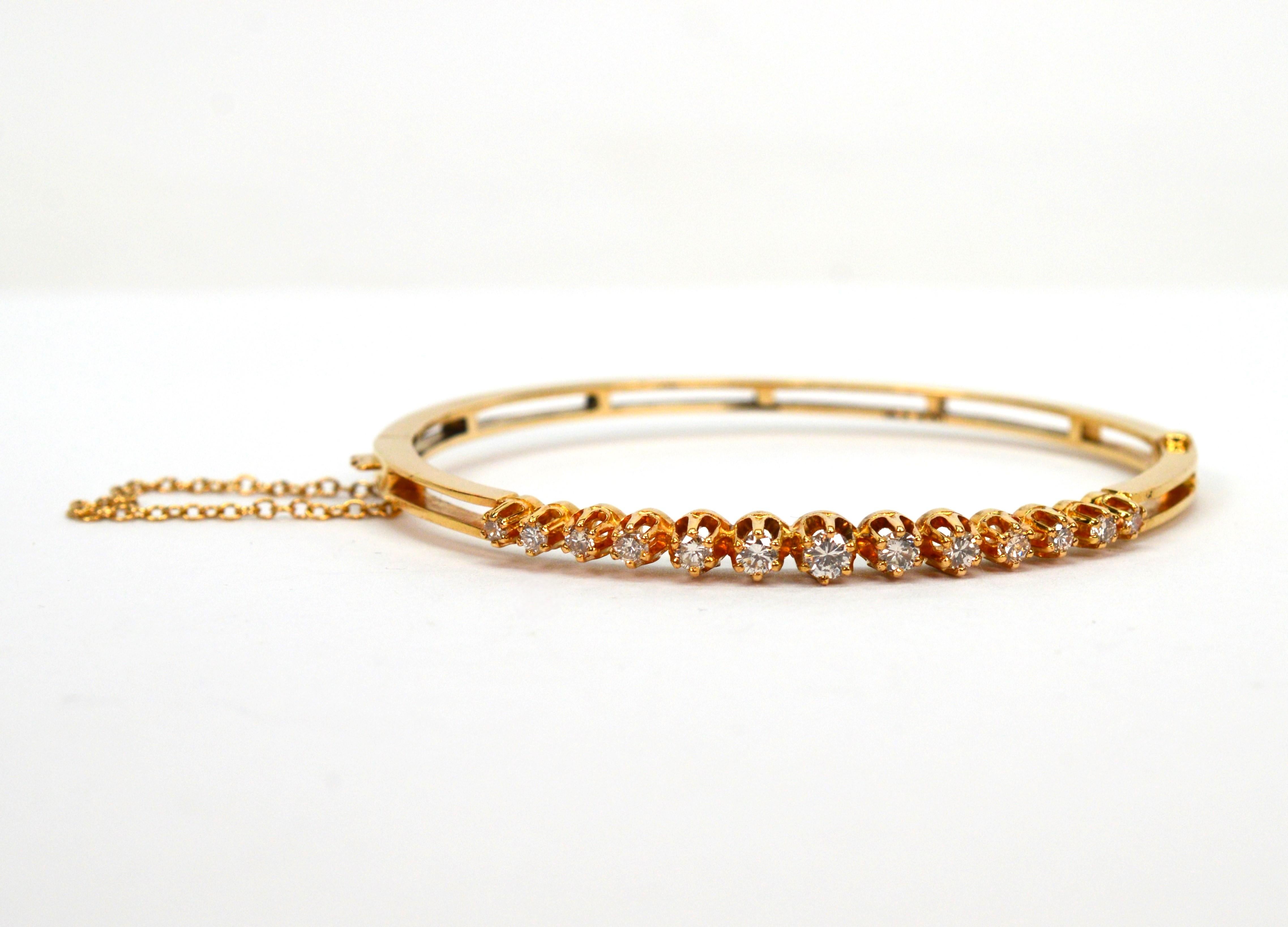 Shimmering  across the front of this very pretty 14 karat yellow gold princess style bangle bracelet are thirteen round faceted H/VS diamonds, .40 ct. TW, that are beautifully showcased by their meticulously crafted raised prong settings. Slender