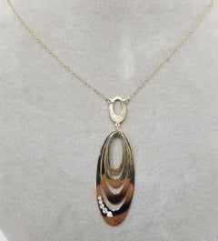 14 Karat Gold Oval Pendant Has Round Cut Diamond in the Middle and 5 Round